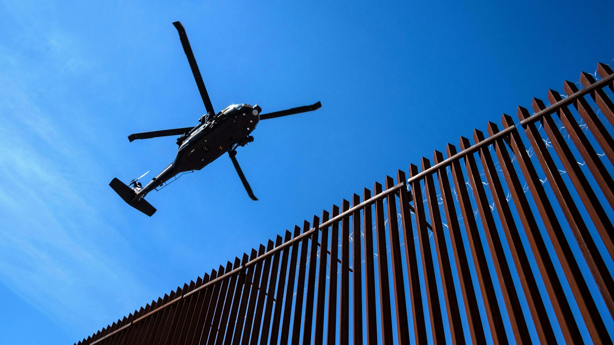 A US border patrol helicopter overflies the US-Mexico border fence as US President Donald Trump visits Calexico, California, as seen from Mexicali, Baja California state, Mexico, on April 5, 2019. - President Donald Trump flew Friday to visit newly built fencing on the Mexican border, even as he retreated from a threat to shut the frontier over what he says is an out-of-control influx of migrants and drugs.