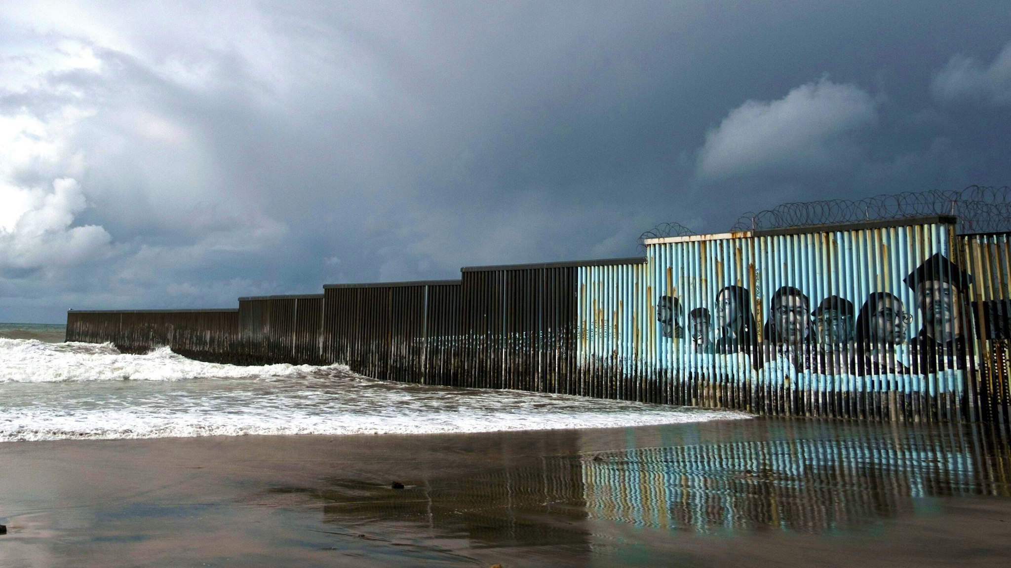 TOPSHOT - Waves crash on the US-Mexico border fence as winter storm clouds are seen over Playas de Tijuana, Baja California state, Mexico, on January 29, 2021. - A winter storm is expected to hit northwestern Mexico.