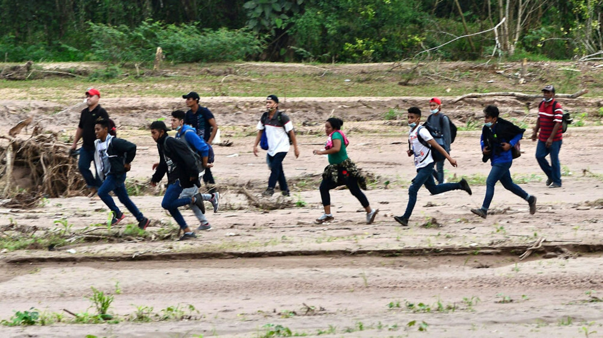 Migrants heading to the border with Guatemala on their way to the United States, cross the dried riverbed of the Copan River in the municipality of Santa Rita, in the Honduran department of Copan, on January 15, 2021. - Hundreds of asylum seekers are forming new migrant caravans in Honduras, planning to walk thousands of kilometers through Central America to the United States via Guatemala and Mexico, in search of a better life under the new administration of President-elect Joe Biden.