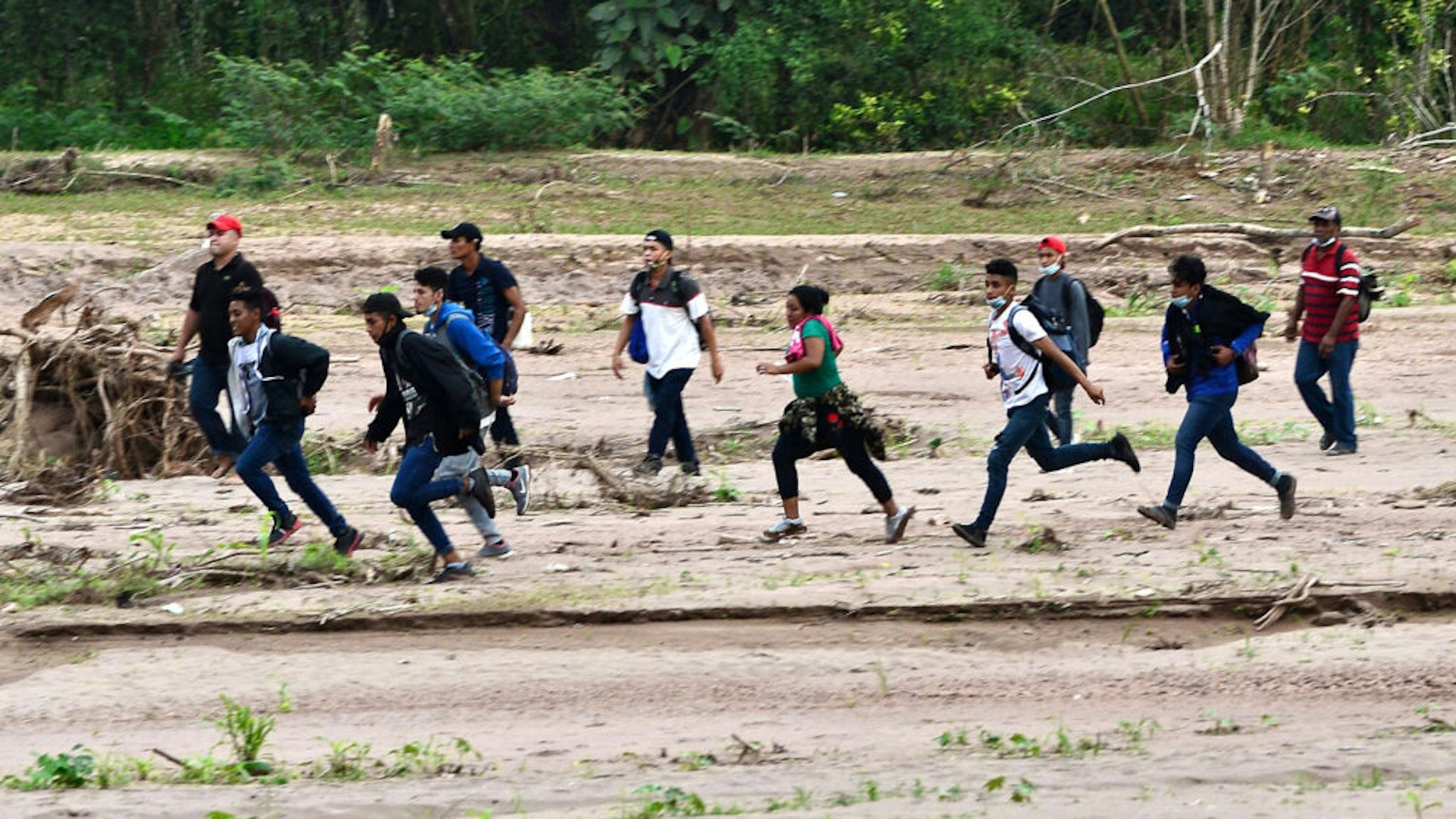 Migrants heading to the border with Guatemala on their way to the United States, cross the dried riverbed of the Copan River in the municipality of Santa Rita, in the Honduran department of Copan, on January 15, 2021. - Hundreds of asylum seekers are forming new migrant caravans in Honduras, planning to walk thousands of kilometers through Central America to the United States via Guatemala and Mexico, in search of a better life under the new administration of President-elect Joe Biden.