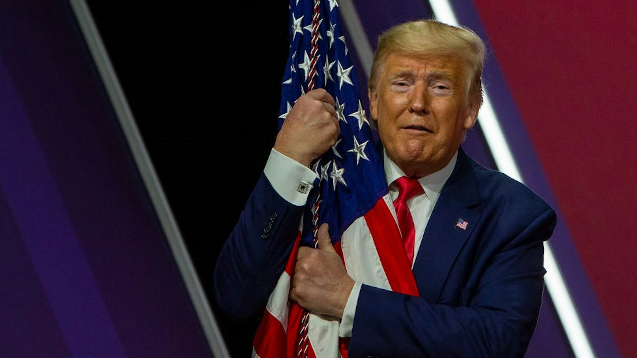 NATIONAL HARBOR, MARYLAND - FEBRUARY 29: US President Donald Trump hugs the flag at the annual Conservative Political Action Conference (CPAC) at Gaylord National Resort &amp; Convention Center February 29, 2020 in National Harbor, Maryland. Conservatives gather at the annual event to discuss their agenda. (Photo by