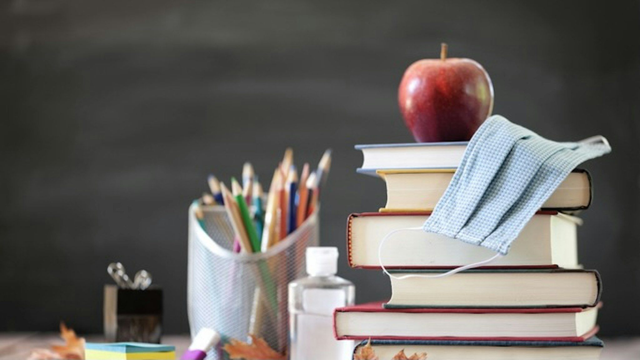 Back to School with Face Mask - stock photo Back to School. Stack of Books with Apple on Top and protective face mask