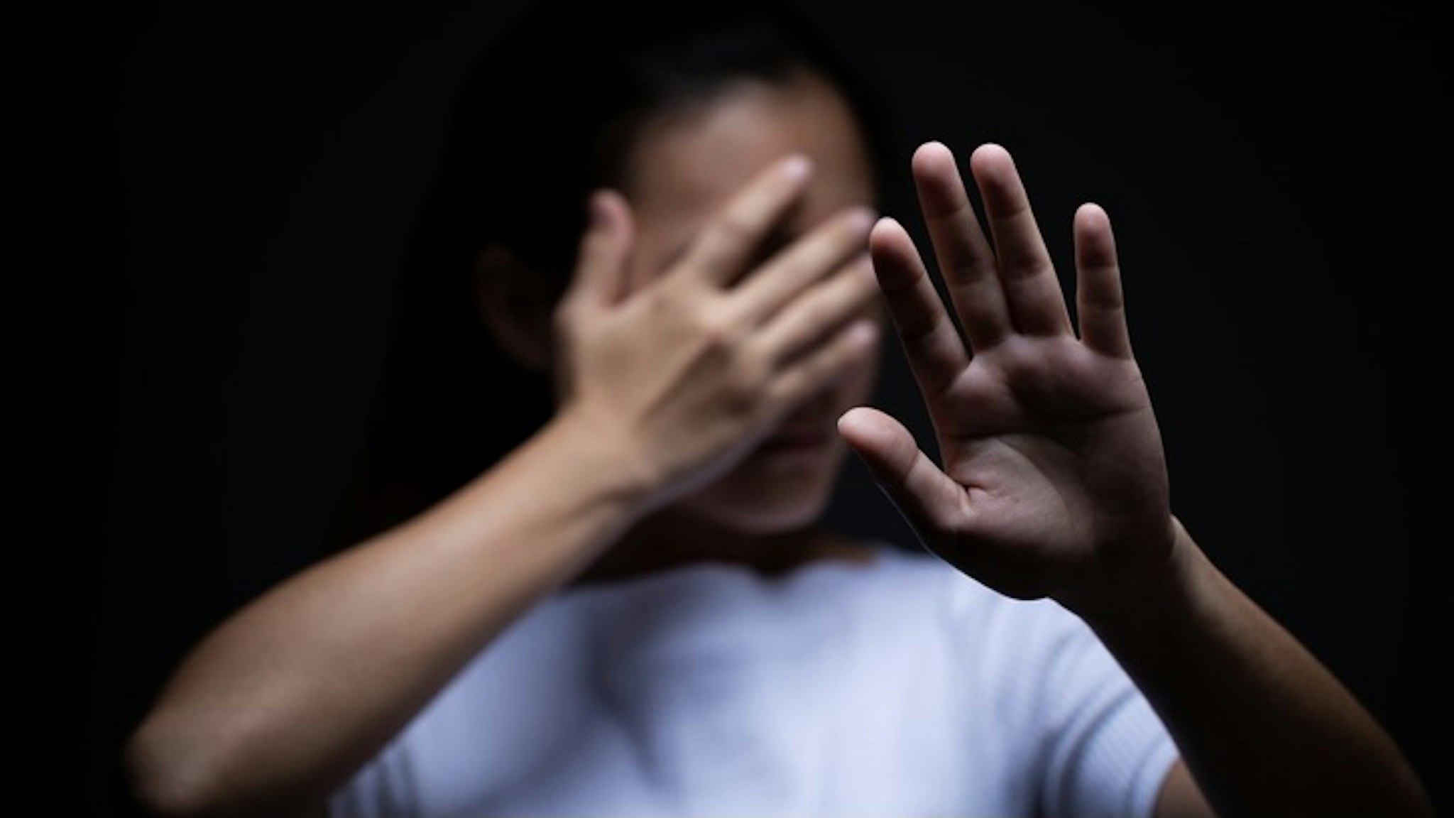 Sadness of a woman in the dark Sad Woman Covering Face With Hand Against Black Background - stock photo