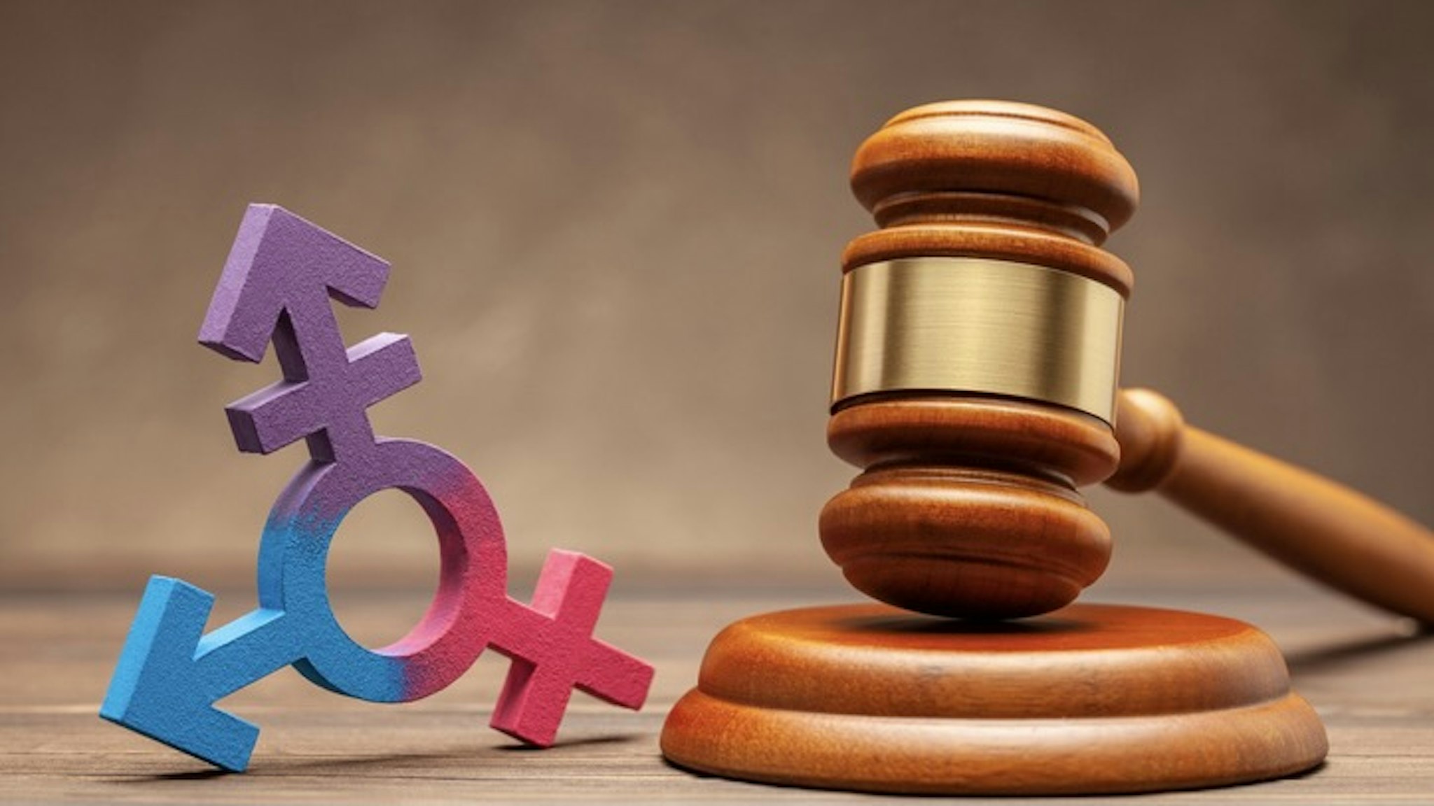 Transgender symbol and judge gavel on brown background. Concept of prohibition or permission for parade or marriage - stock photo Transgender symbol and judge gavel on brown background. Concept of prohibition or permission for parade or marriage.