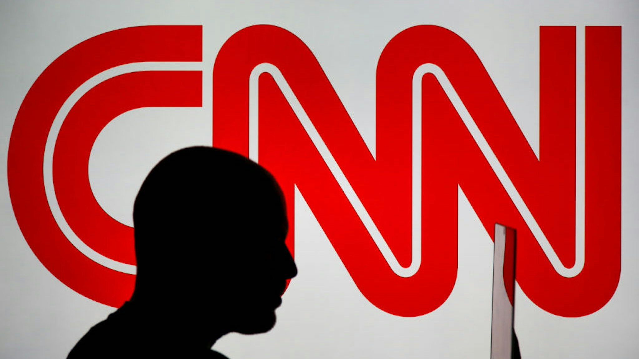 A man is seen holding with a smart device in front of a CNN logo in this photo illustration on 2 July, 2017. (Photo by Jaap Arriens/NurPhoto)