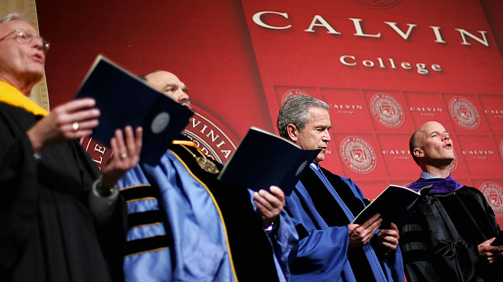 GRAND RAPIDS, UNITED STATES: US President George W. Bush looks at his hymnal while others sing before delivering the commencement address at Calvin College 21 May 2005 in the Calvin College Field House in Grand Rapids, Michigan