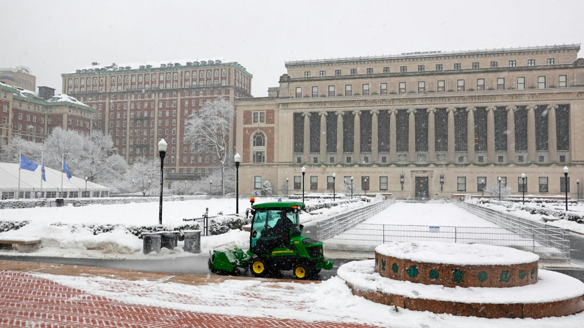 Tractor with roller brush and blower removing snow from walkways on the Columbia University campus area in New York.