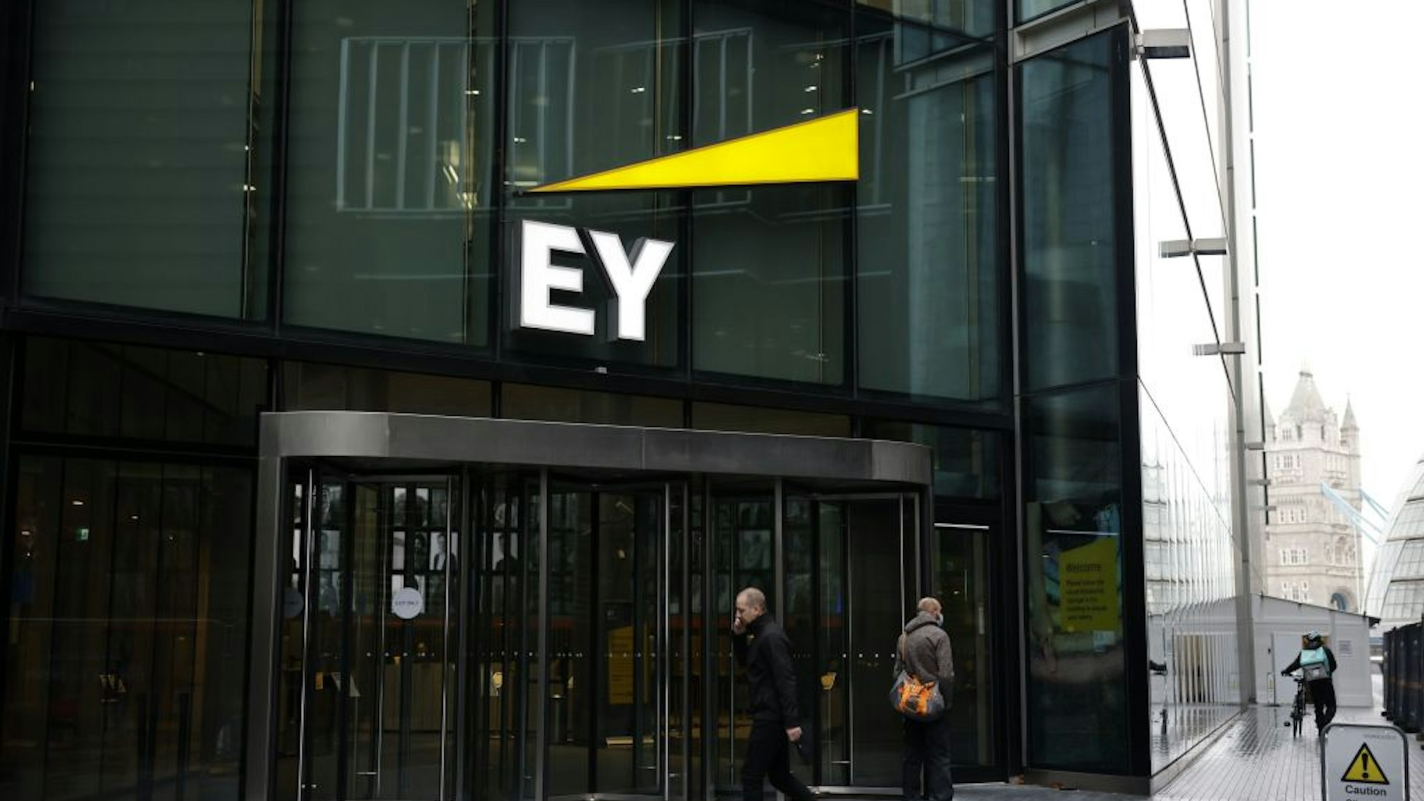 Pedestrians walk past the offices of accounting and auditing firm EY, formerly Ernst &amp; Young, in London on November 20, 2020. - Britain's audit sector, dominated by the so-called Big Four accountancy giants, is shortly expected to discover how it must reinvent itself amid a series of probes into alleged corruption, including one linked to the collapse of German electronic payments group Wirecard. The Department for Business, Energy and Industrial Strategy (BEIS) is reportedly set to publish reform proposals before Christmas amid fraudulent probes into EY-linked activities at Denmark's Danske Bank and Wirecard. EY has been accused of failing to warn about suspicious transactions at Danish bank Danske Bank worth billions of euros.
