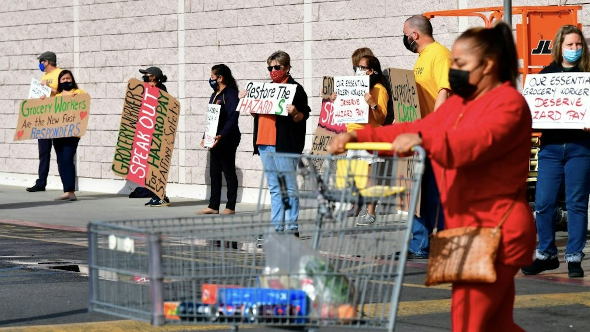 Supermarket workers hold placards in protest in front of a Food 4 Less supermarket in Long Beach, California on February 3, 2021, after a decision by owner Kroger to close two supermarkets rather than pay workers an additional $4.00 in "hazard pay" for their continued work during the coronavirus pandemic. - Kroger, which owns Ralphs and food 4 Less, said it will close one of each store in April after the Long Beach city council passed a law mandating "hazard pay" for grocery store workers. Long Beach was the first city in the region to approve a hazard pay ordinance. (Photo by Frederic J. BROWN / AFP) (Photo by FREDERIC J. BROWN/AFP via Getty Images)