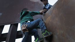 Immigrant Caravan Members Continue To Gather At U.S.-Mexico Border TIJUANA, MEXICO - DECEMBER 02: A boy is hoisted by fellow members of the migrant caravan over the U.S.-Mexico border fence on December 2, 2018 from Tijuana, Mexico. Numerous members of the caravan were able to cross over from Tijuana to San Diego and were quickly taken into custody by U.S. Border Patrol agents. Most had planned to request political asylum in the United States after traveling more than 6 weeks from Central America. (Photo by John Moore/Getty Images)