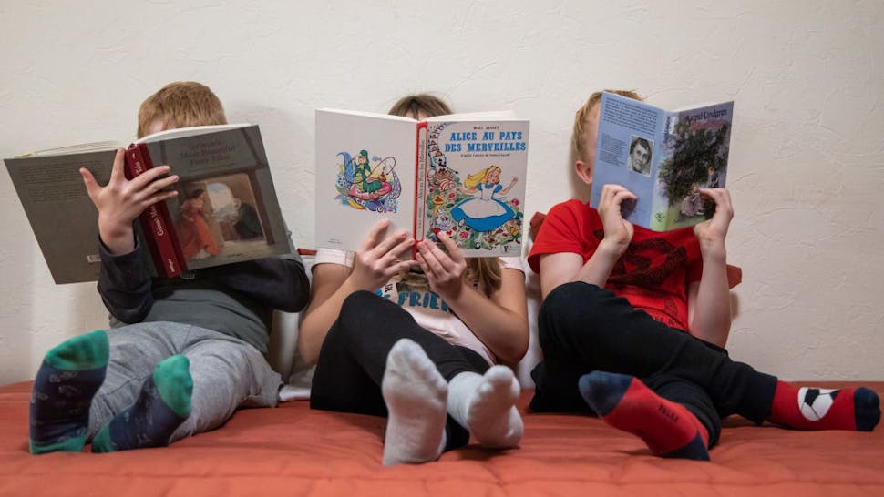 children reading 04 November 2019, France (France), Grosbliederstorff: ILLUSTRATION - Three children each read an English (l), a French (M) and a German book. (to dpa "The book is dead - or not?") Photo: Daniel Karmann/dpa