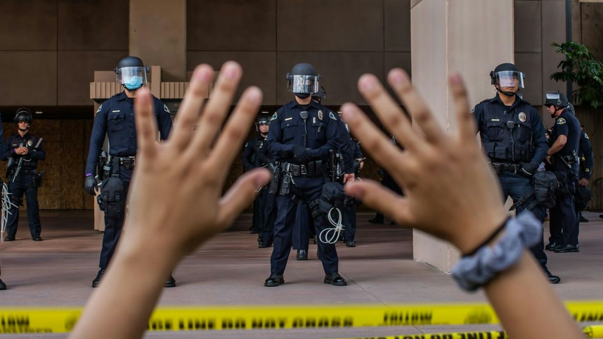 A demonstrator holds her hands up while she kneels in front of the Police at the Anaheim City Hall on June 1, 2020 in Anaheim, California, during a peaceful protest over the death of George Floyd. - Major US cities -- convulsed by protests, clashes with police and looting since the death in Minneapolis police custody of George Floyd a week ago -- braced Monday for another night of unrest. More than 40 cities have imposed curfews after consecutive nights of tension that included looting and the trashing of parked cars.