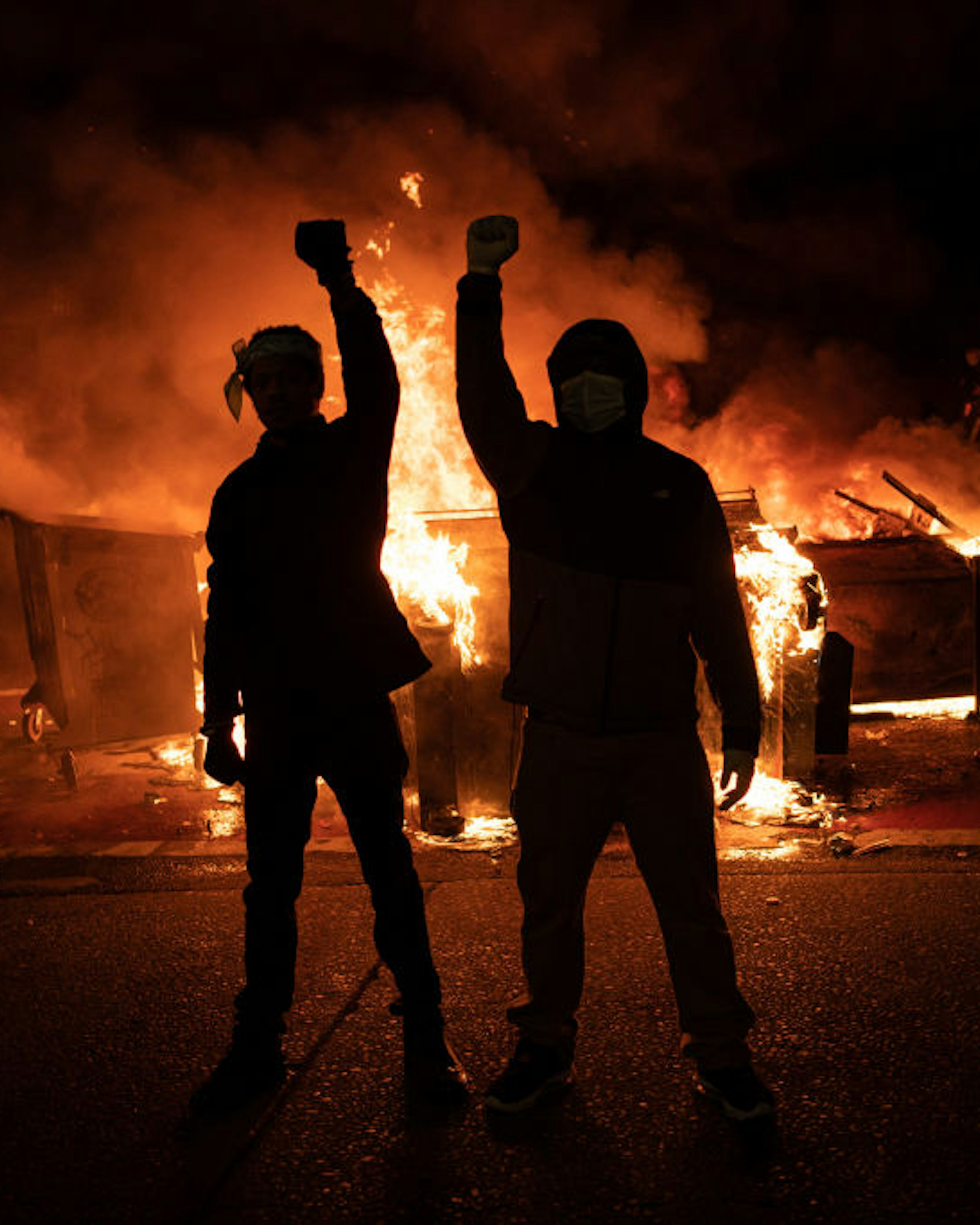 SEATTLE, WA - JUNE 08: Demonstrators raise their fists as a fire burns in the street after clashes with law enforcement near the Seattle Police Departments East Precinct shortly after midnight on June 8, 2020 in Seattle, Washington. Earlier in the evening, a suspect drove into the crowd of protesters and shot one person, which happened after a day of peaceful protests across the city. Later, police and protesters clashed violently during ongoing Black Lives Matter demonstrations following the death of George Floyd. (Photo by David Ryder/Getty Images)