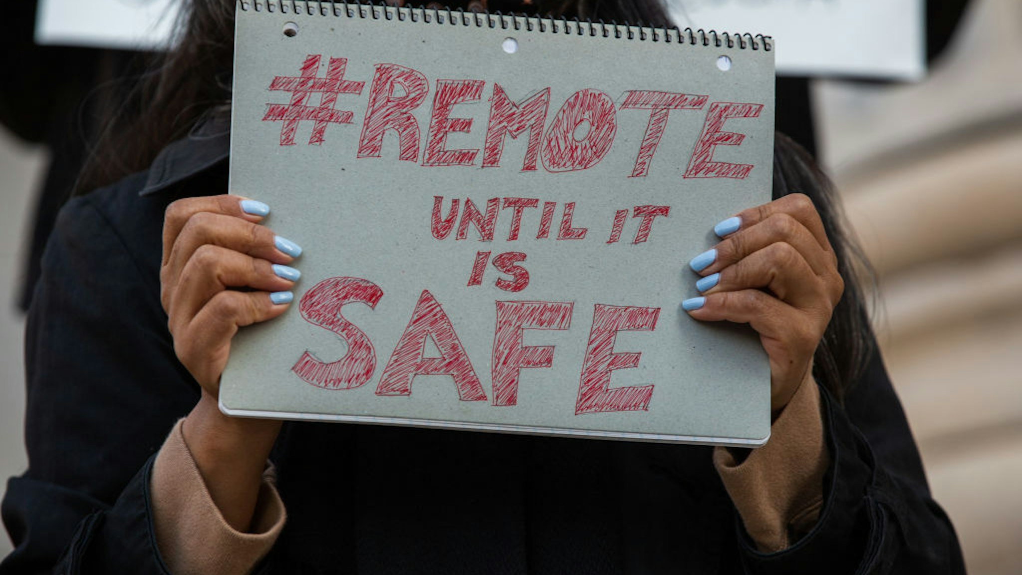 A demonstrator holds a sign reading "#Remote until it is safe" during a protest outside Brooklyn Borough Hall in the Brooklyn borough of New York, U.S. on Monday, Sept. 21, 2020.