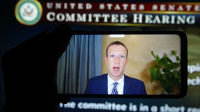 KIEV, UKRAINE - 2020/10/29: In this photo illustration, Facebook CEO Mark Zuckerberg seen on a mobile screen as he remotely testifies during the hearing of U.S. Senate Committee on Commerce, Science, and Transportation titled "Does Section 230's Sweeping Immunity Enable Big Tech Bad Behavior?" on Capitol Hill in Washington, D.C., the United States. (Photo Illustration by Pavlo Conchar/SOPA Images/LightRocket via Getty Images)