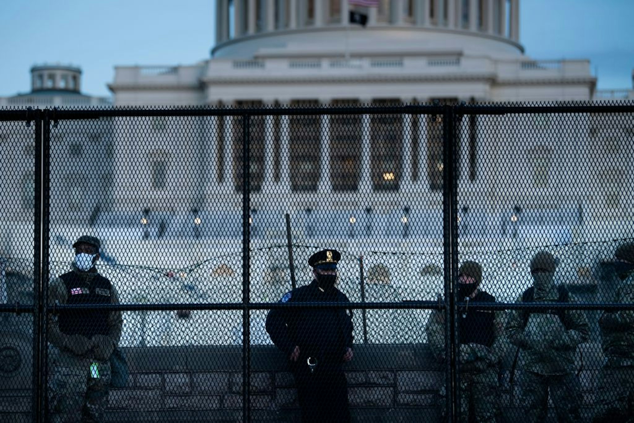 TOPSHOT - A Capitol Police officer stands with members of the National Guard behind a crowd control fence surrounding Capitol Hill a day after a pro-Trump mob broke into the US Capitol on January 7, 2021, in Washington, DC.