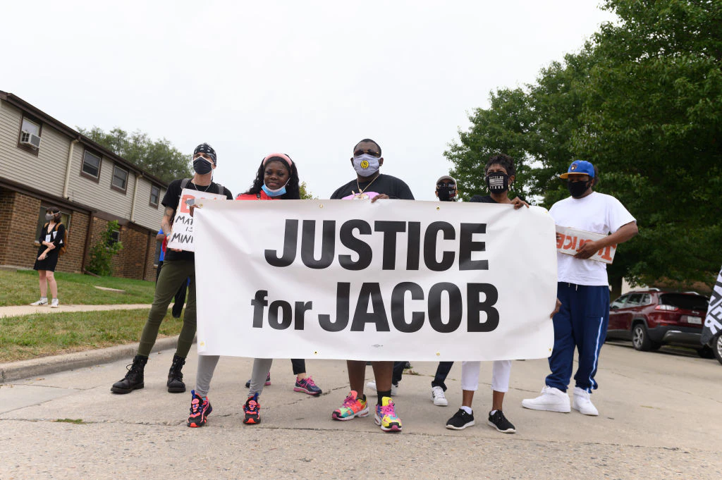 Protesters hold a banner during a community celebration and call for justice for Jacob Blake as grassroots group MoveOn flies an airplane banner and drives a mobile billboard calling on voters to "Reject Trump's Violence," in response to Donald Trump's visit on September 01, 2020 in Kenosha, Wisconsin.