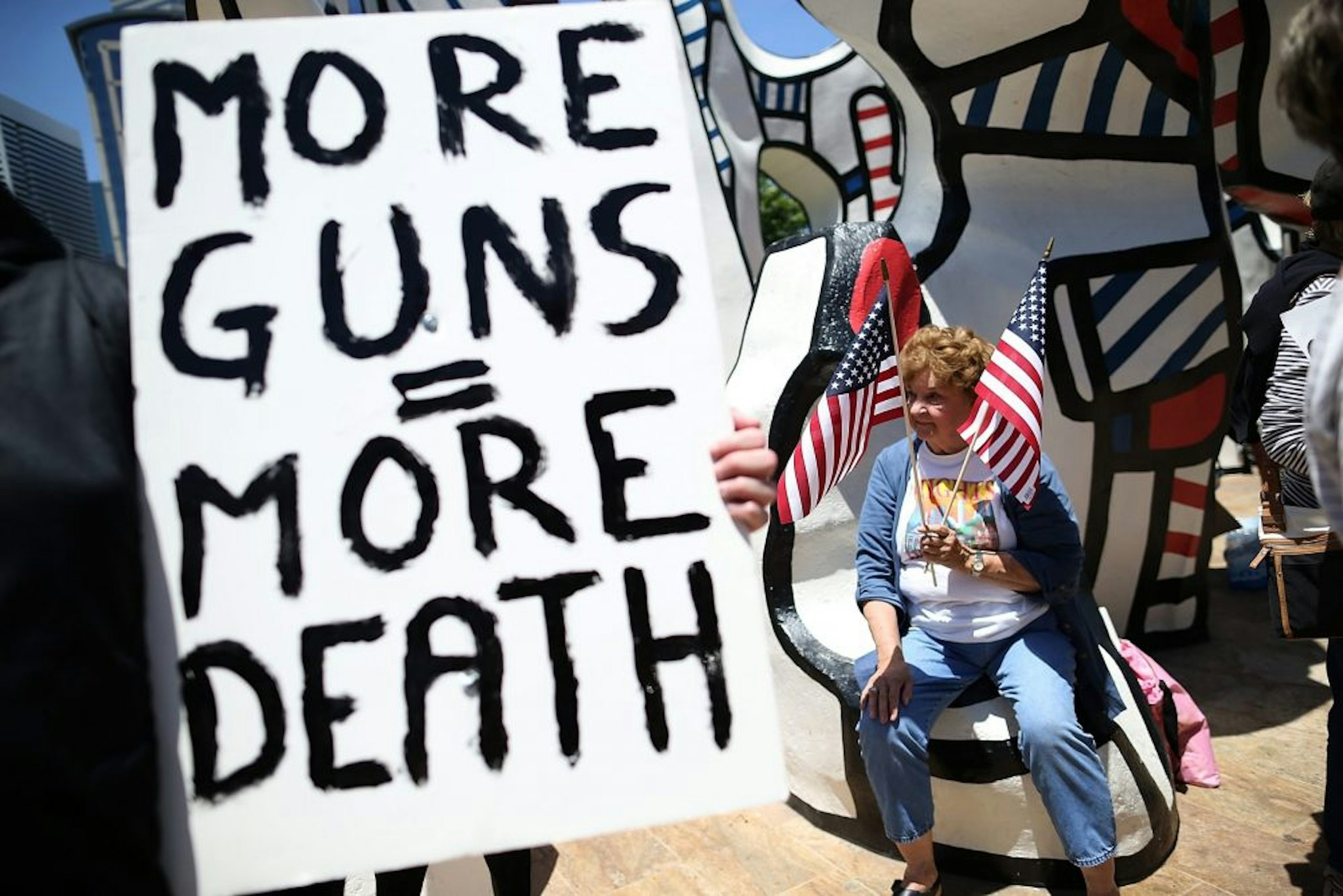 HOUSTON, TX - MAY 04: A protestor holds American flags during a demonstration in favor of gun regulation outside of the 2013 NRA Annual Meeting and Exhibits at the George R. Brown Convention Center on May 4, 2013 in Houston, Texas. More than 70,000 peope are expected to attend the NRA's 3-day annual meeting that features nearly 550 exhibitors, gun trade show and a political rally. The Show runs from May 3-5.