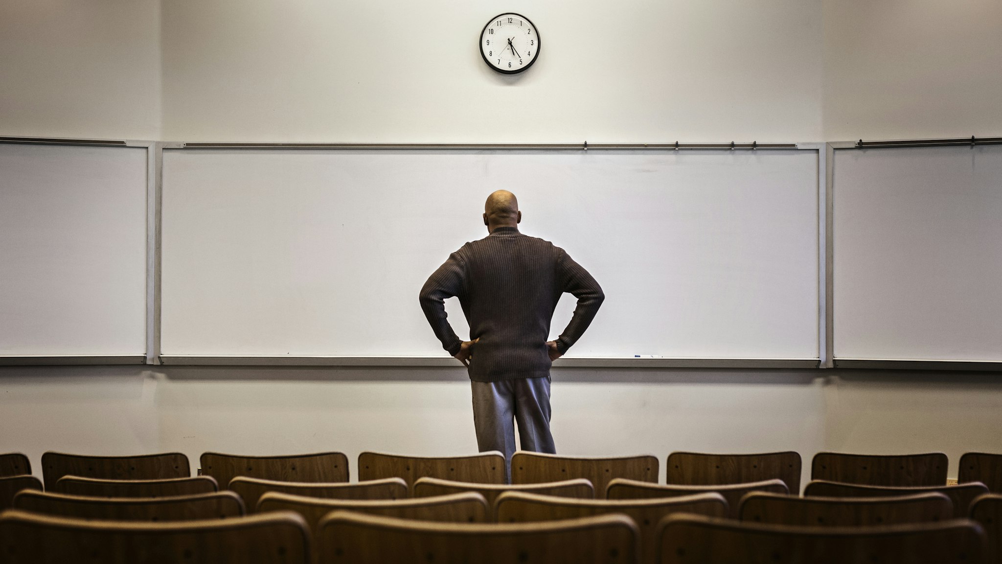 Professor standing in empty classroom - stock photo