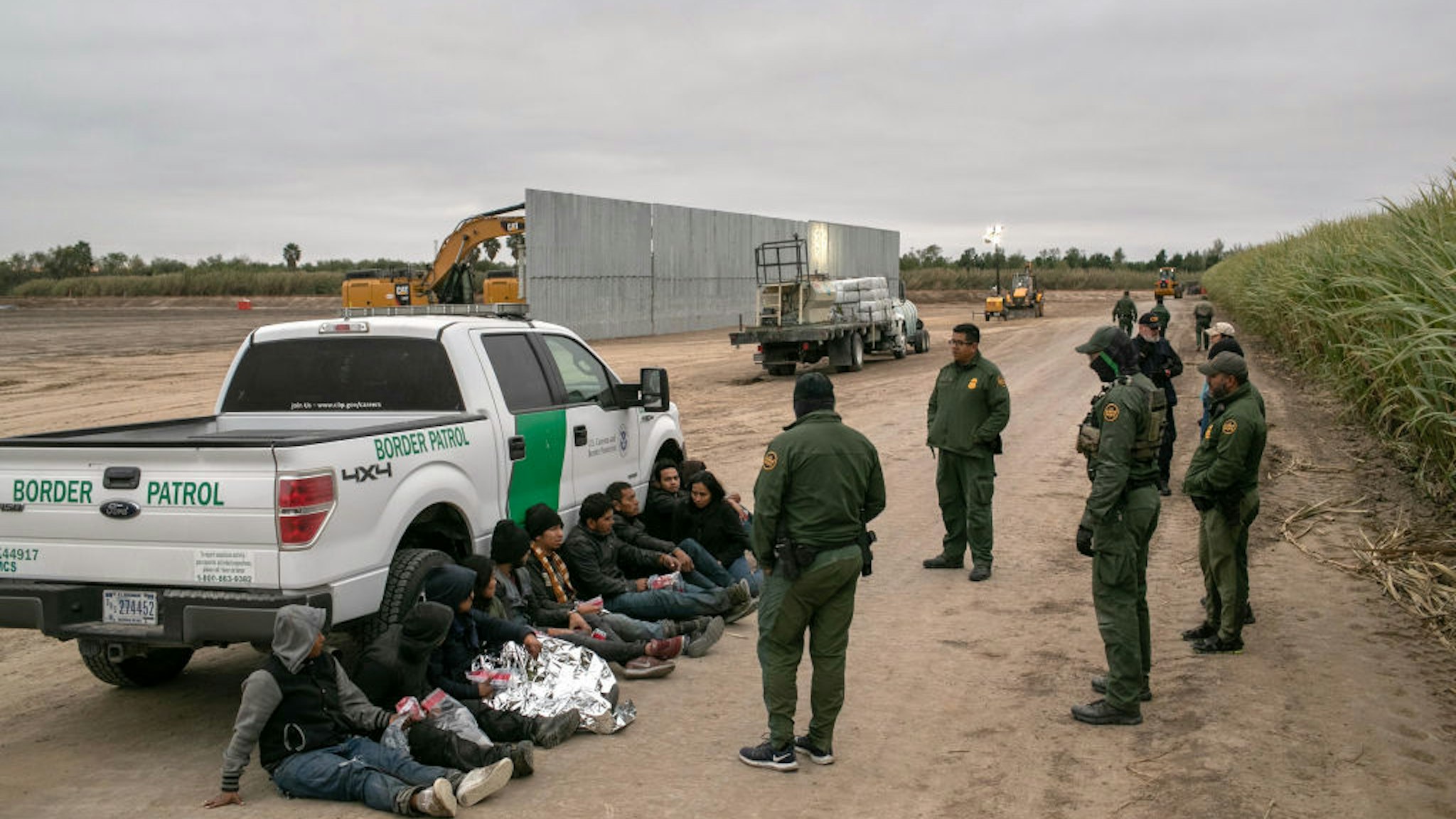 MISSION, TEXAS - DECEMBER 11: U.S. Border Patrol agents detain undocumented immigrants caught near a section of privately-built border wall under construction on December 11, 2019 near Mission, Texas. The hardline immigration group We Build The Wall is funding construction of the wall on private land along the Rio Grande, which forms the border with Mexico. The group, led by former Trump strategist Stephen Bannon claims to have raised tens of millions of dollars in a GoFundMe drive to build sections of wall along stretches of the U.S. southwest border with Mexico. (Photo by John Moore/Getty Images)