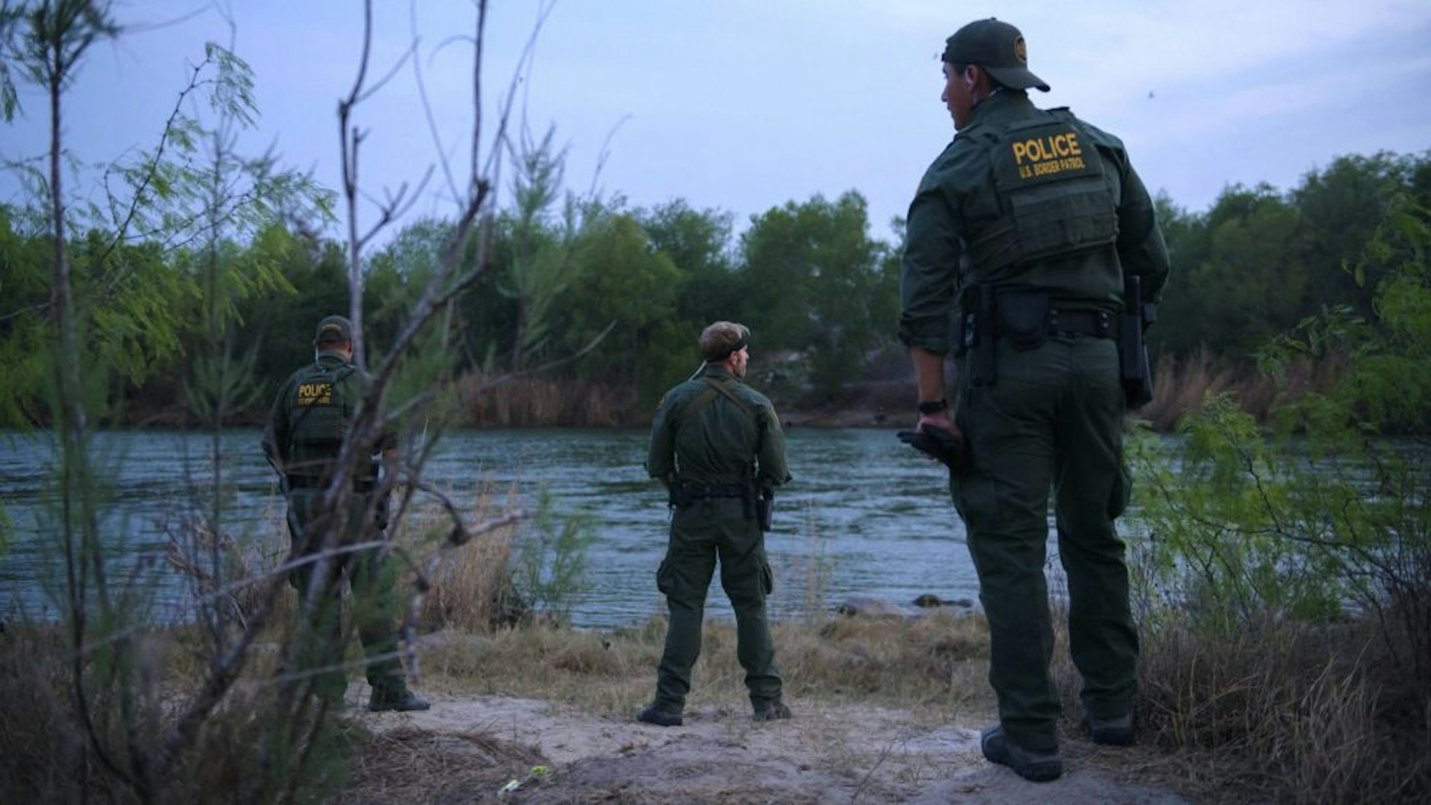 US border patrol agents stand on March 27, 2021 before the Rio Grande river that separates the US and Mexico, in the US border city of Roma.