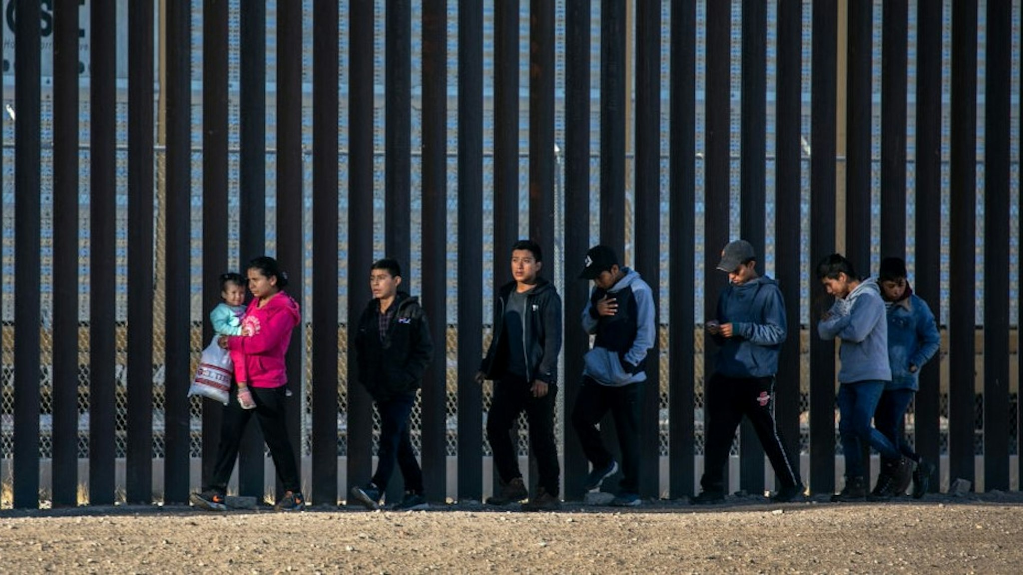 CIUDAD JUAREZ, MEXICO - MARCH 17: Undocumented immigrants walk along the U.S.-Mexico border wall after they ran across the shallow Rio Grande into El Paso on March 17, 2021 in Ciudad Juarez, Mexico. U.S. immigration officials are dealing with an immigrant surge along the southwest border with Mexico. (Photo by