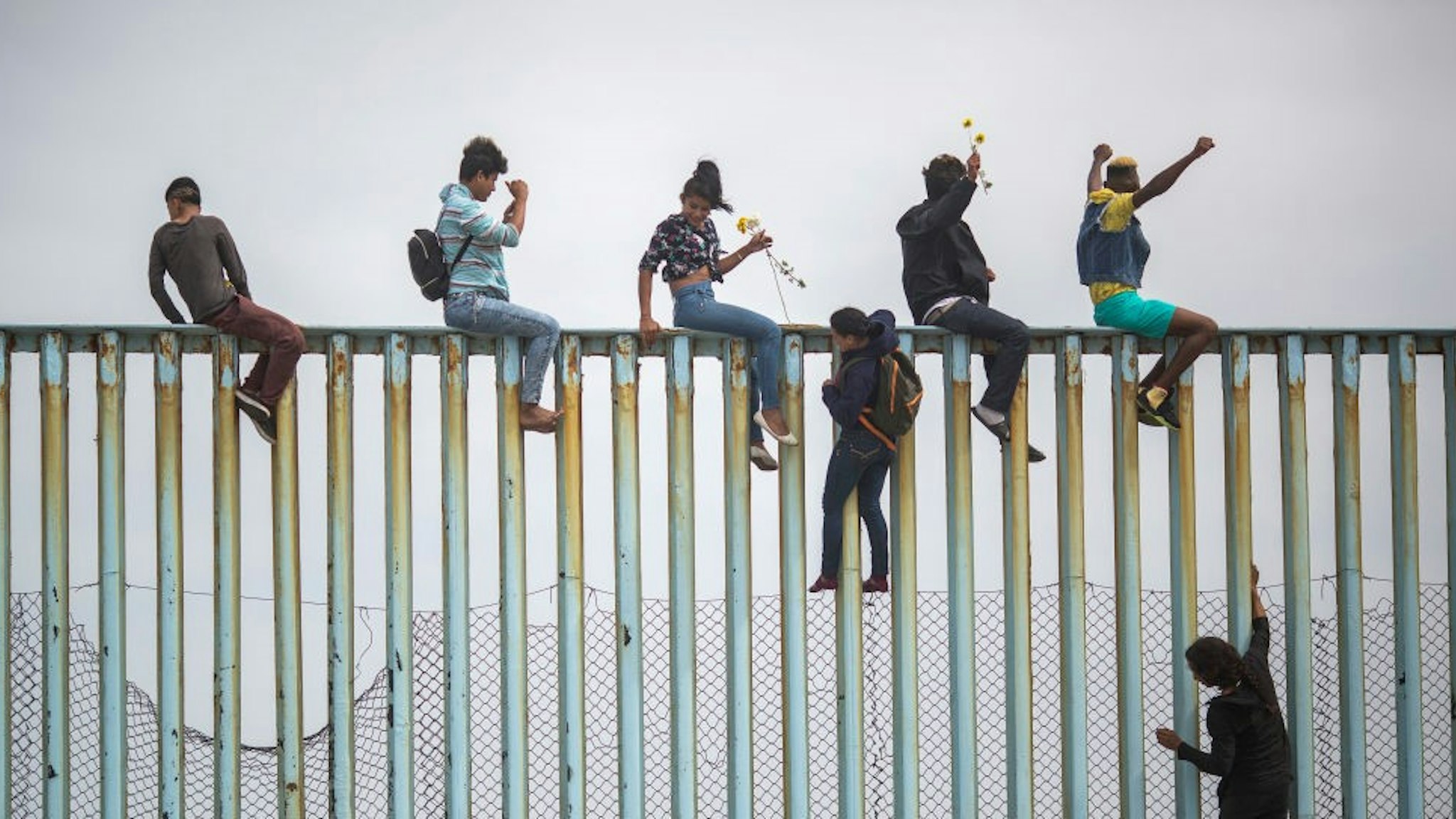 TIJUANA, MEXICO - APRIL 29: People climb a section of border fence to look toward supporters in the U.S. as members of a caravan of Central American asylum seekers arrive to a rally on April 29, 2018 in Tijuana, Baja California Norte, Mexico. More than 300 immigrants, the remnants of a caravan of Central Americans that journeyed across Mexico to ask for asylum in the United States, have reached the border to apply for legal entry. (Photo by