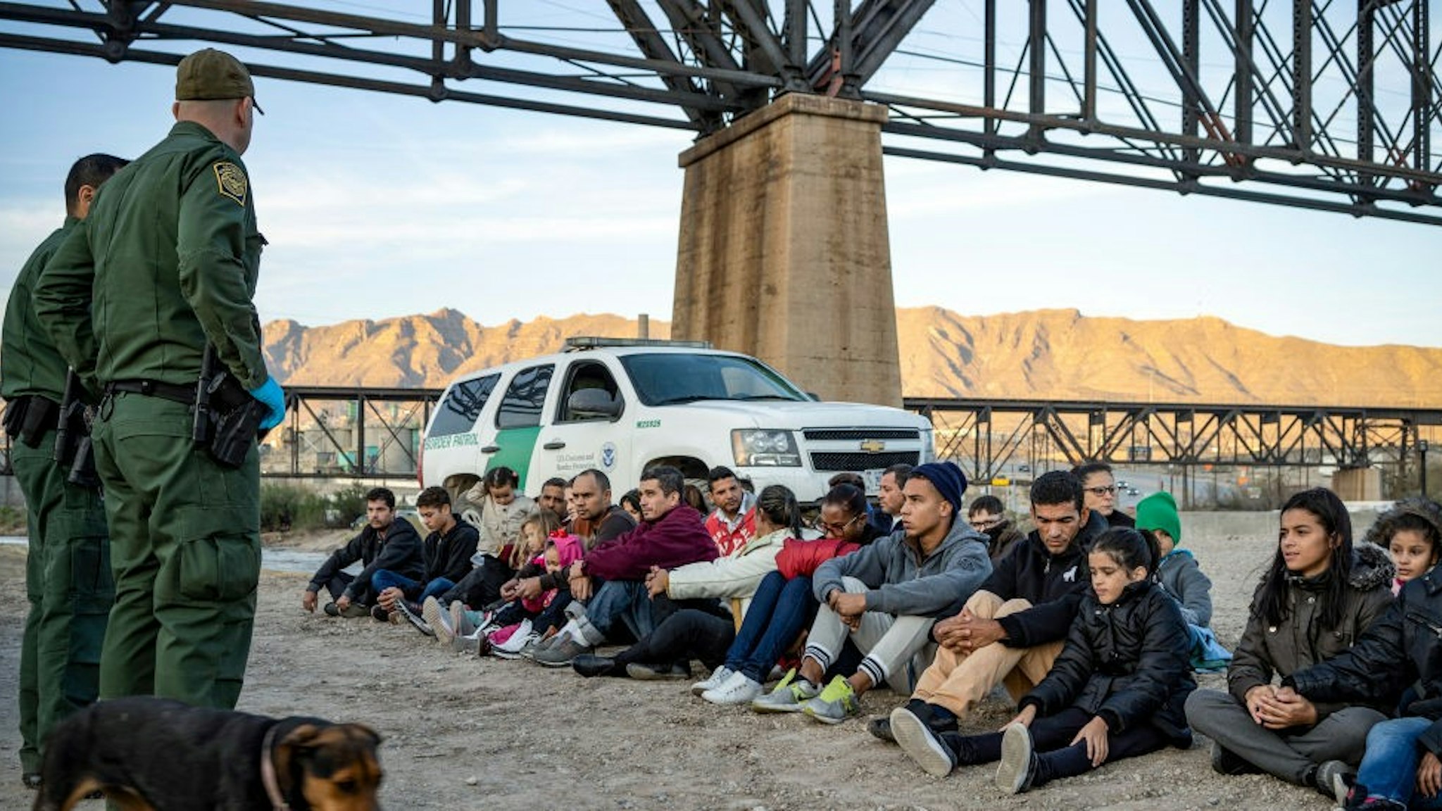 TOPSHOT - A group of about 30 Brazilian migrants, who had just crossed the border, sit on the ground near US Border Patrol agents, on the property of Jeff Allen, who used to run a brick factory near Mt. Christo Rey on the US-Mexico border in Sunland Park, New Mexico on March 20, 2019. - The militia members say they will patrol the US-Mexico border near Mt. Christo Rey, "Until the wall is built." In recent months, thousands of Central Americans have arrived in Mexico in several caravans in the hope of finding a better life in the United States. US President Donald Trump has branded such migrants a threat to national security, demanding billions of dollars from Congress to build a wall on the southern US border. (Photo by