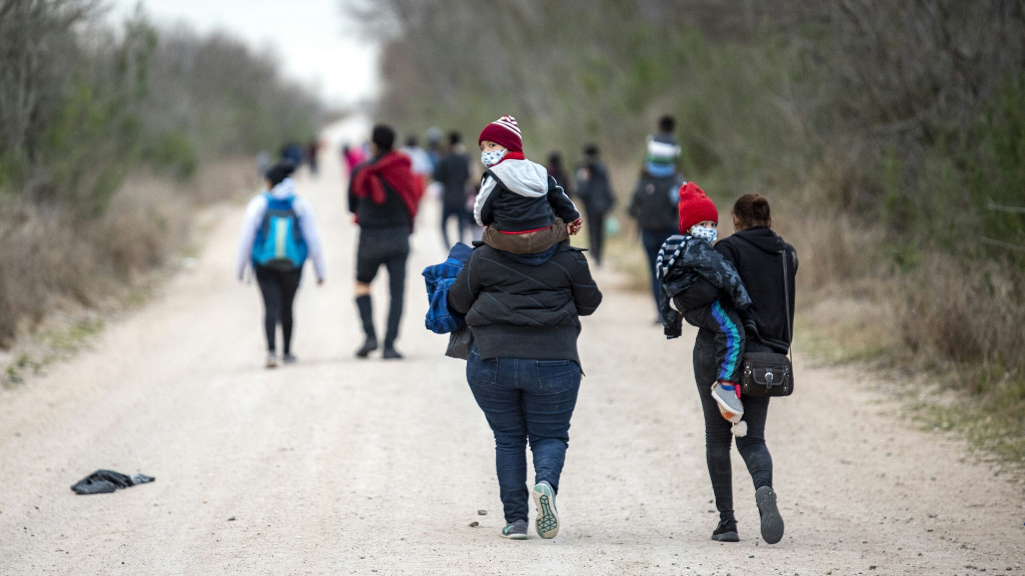 Migrant families walk toward a Customs and Border Patrol processing center near Mission, Texas, U.S., on Tuesday, March 2, 2021. President Biden told his Mexican counterpart, Andres Manuel Lopez Obrador, during their virtual meeting last week that he agreed on the need to increase legal paths to immigration, two Mexican officials said.