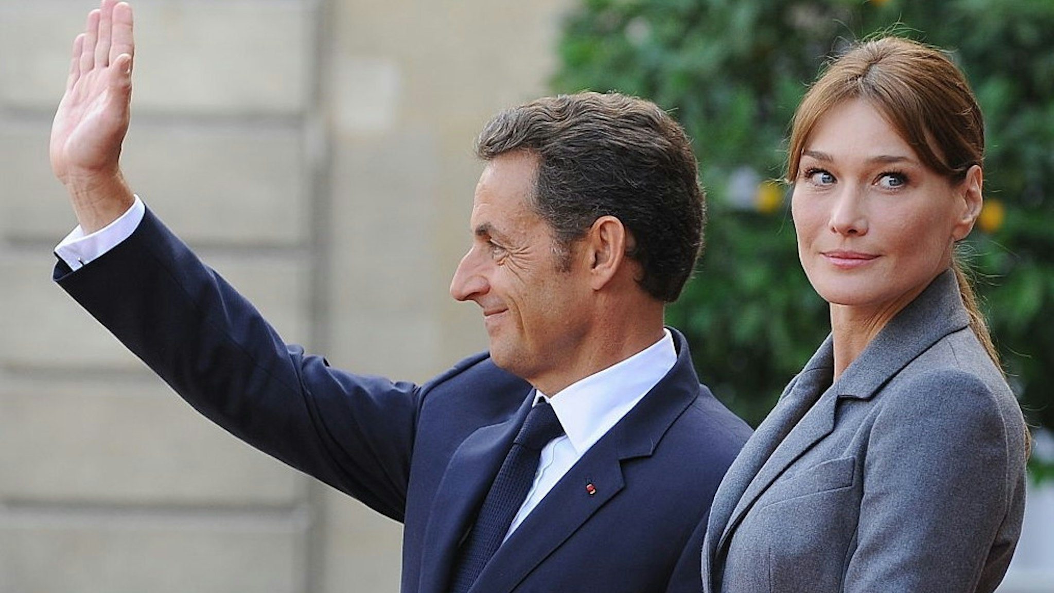 French President Nicolas Sarkozy and First Lady Carla Bruni-Sarkozy stand on the red carpet outside the Elysee Palace as Pope Benedict XVI departs. (Photo by