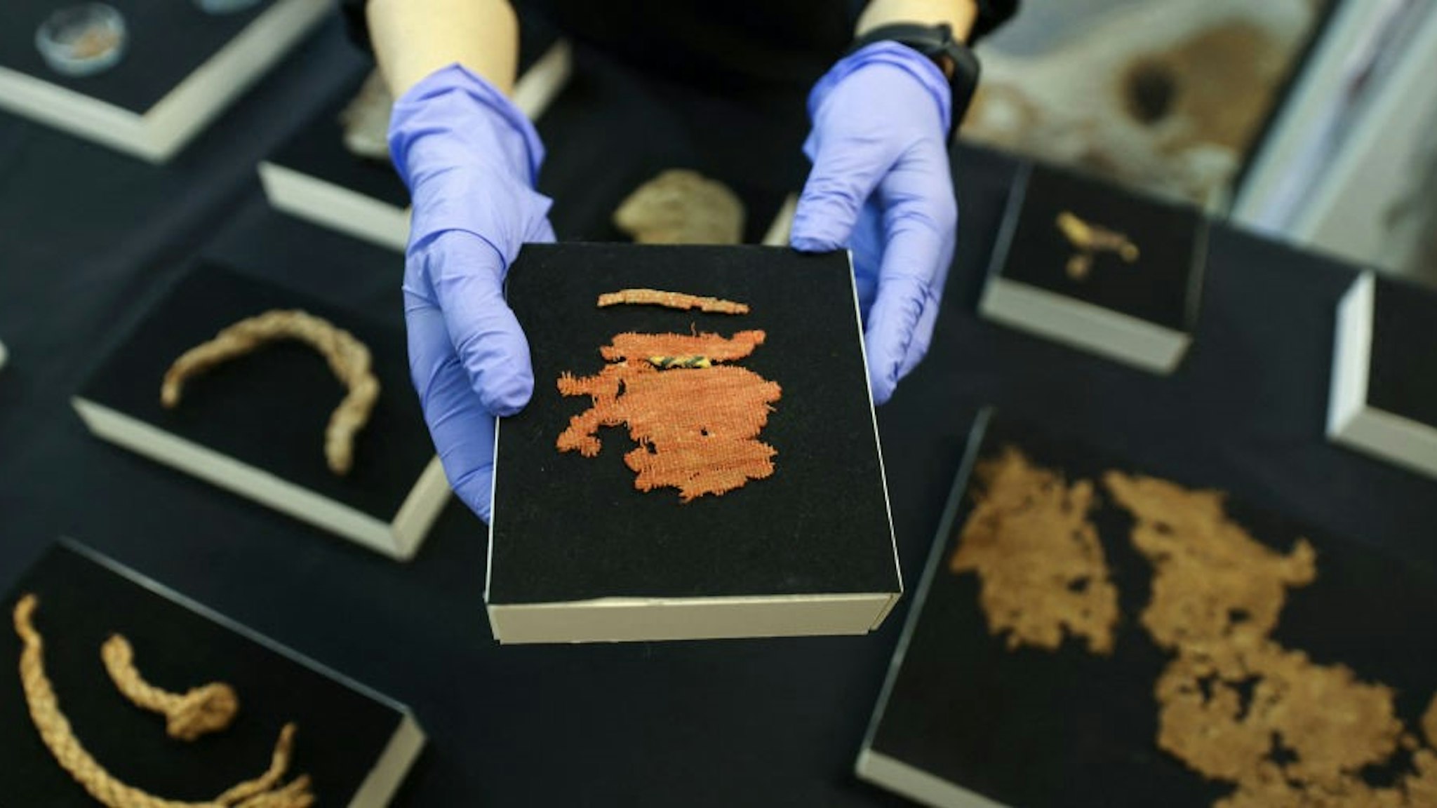 An archaeologist at the Israel Antiquities Authority (IAA) shows a cloth fragment from the Bar Kochba Jewish revolt period dating back to 132136 CE, excavated from an area in the Judean Desert, after conservation work is done at the IAA's Dead Sea conservation laboratory in Jerusalem, on March 16, 2021. - Israel described the find, which includes a cache of rare coins, a six-millennia-old skeleton of a child and basket it described as the oldest in the world, at over 10,000 years, as one of the most significant since the Dead Sea Scrolls. The fragments, found following a survey in a desert area spanning southern Israel and the occupied West Bank, include passages in Greek from the Book of the Twelve Minor Prophets including the books of Zechariah and Nahum, the IAA said. (Photo by MENAHEM KAHANA / AFP) (Photo by