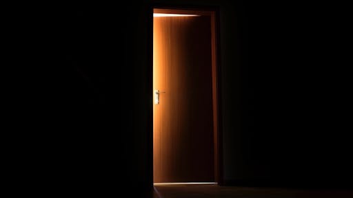 05F9F7BA-4218-4473-8DC0-BBD0D6699703_1_201_a Glowing sunlight illuminating the edges of an opening interior door - stock photo