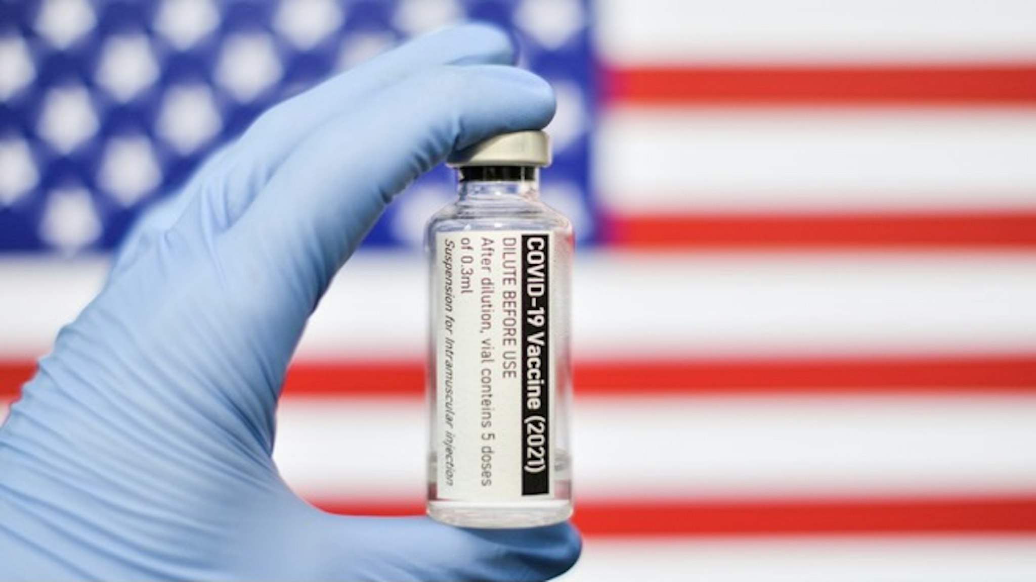 COVID-19 Vaccine on USA Flag. COVID-19 pandemic theme - stock photo Coronavirus Covid-19 concept. Doctor with blue protection medical gloves holds a vaccine bottle. coronavirus covid 19 vaccine research
