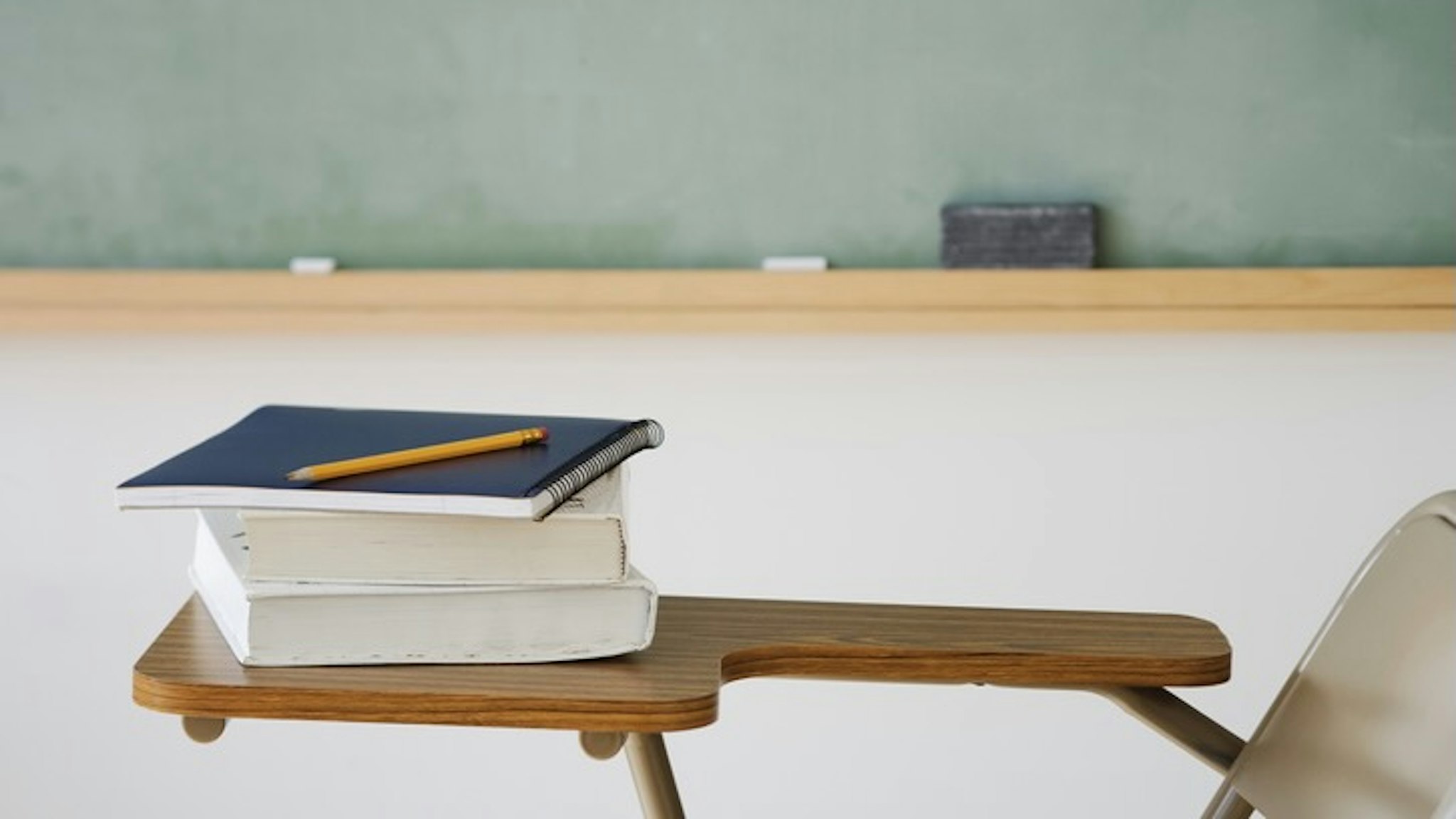 Books and pencil on desk in classroom - stock photo
