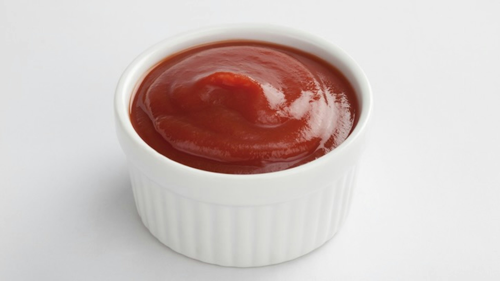 White dip cup filled with ketchup on white background - stock photo Ketchup ramekin.