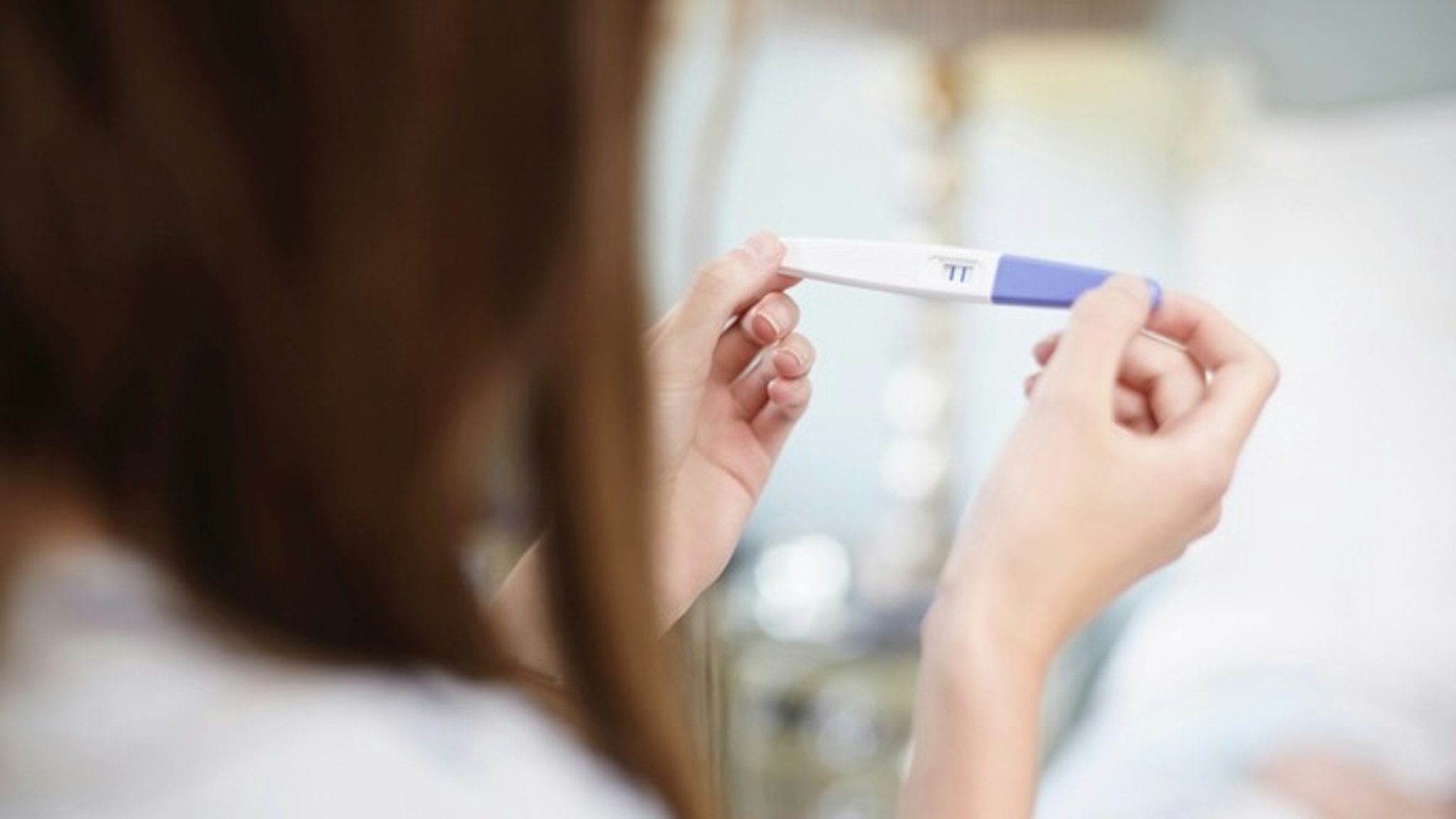 Girl holding a pregnancy test - stock photo