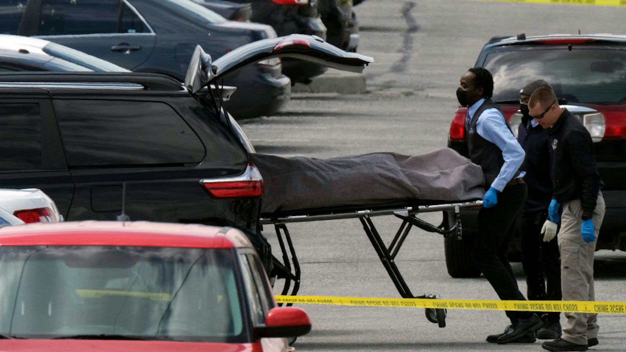 Officials load a body into a vehicle at the site of a mass shooting at a FedEx facility in Indianapolis, Indiana, on April 16, 2021. - A gunman has killed at least eight people at the facility before turning the gun on himself in the latest in a string of mass shootings in the country, authorities said. The incident came a week after President Joe Biden branded US gun violence an "epidemic" and an "international embarrassment" as he waded into the tense debate over gun control, a powerful political issue in the US. (Photo by Jeff Dean / AFP)