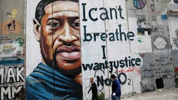 George Floyd People walk past a mural showing the face of George Floyd, an unarmed handcuffed black man who died after a white policeman knelt on his neck during an arrest in the US, painted on a section of Israel's controversial separation barrier in the city of Bethlehem in the occupied West Bank on March 31, 2021. (Photo by EMMANUEL DUNAND/AFP via Getty Images)