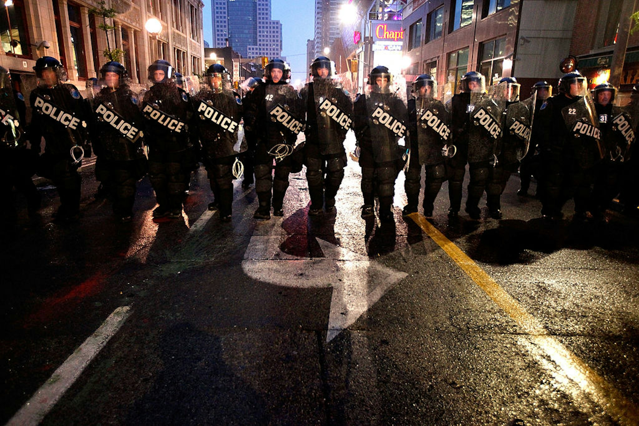 TORONTO, ON - JUNE 26: Police officers in full riot gear advance on anti-G20 demonstrators on Queen Street June 26, 2010 in Toronto, Canada. Earlier in the day violent protesters burned police cars, smashed shop fronts and confronted the force of approximately 20,000 police charged with keeping order during the first day of the G20 Summit