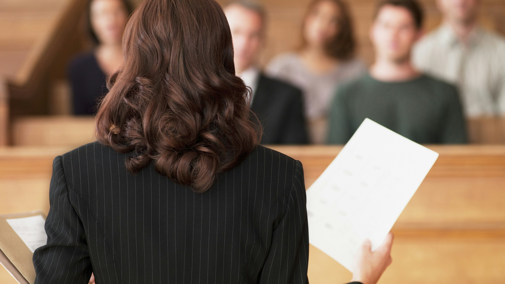 Lawyer holding document and speaking to jury in courtroom - stock photo