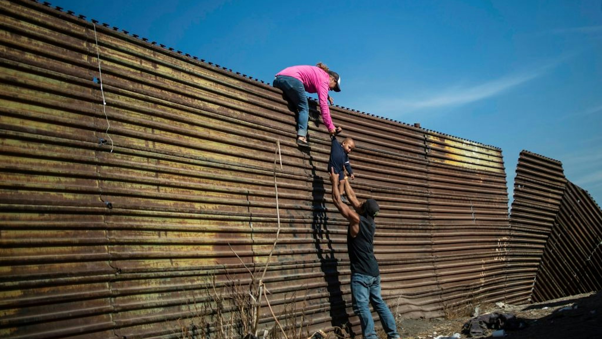 TOPSHOT - A group of Central American migrants climb the border fence between Mexico and the United States, near El Chaparral border crossing, in Tijuana, Baja California State, Mexico, on November 25, 2018. - Hundreds of migrants attempted to storm a border fence separating Mexico from the US on Sunday amid mounting fears they will be kept in Mexico while their applications for a asylum are processed. An AFP photographer said the migrants broke away from a peaceful march at a border bridge and tried to climb over a metal border barrier in the attempt to enter the United States. (Photo by Pedro PARDO / AFP) (Photo by PEDRO PARDO/AFP via Getty Images)