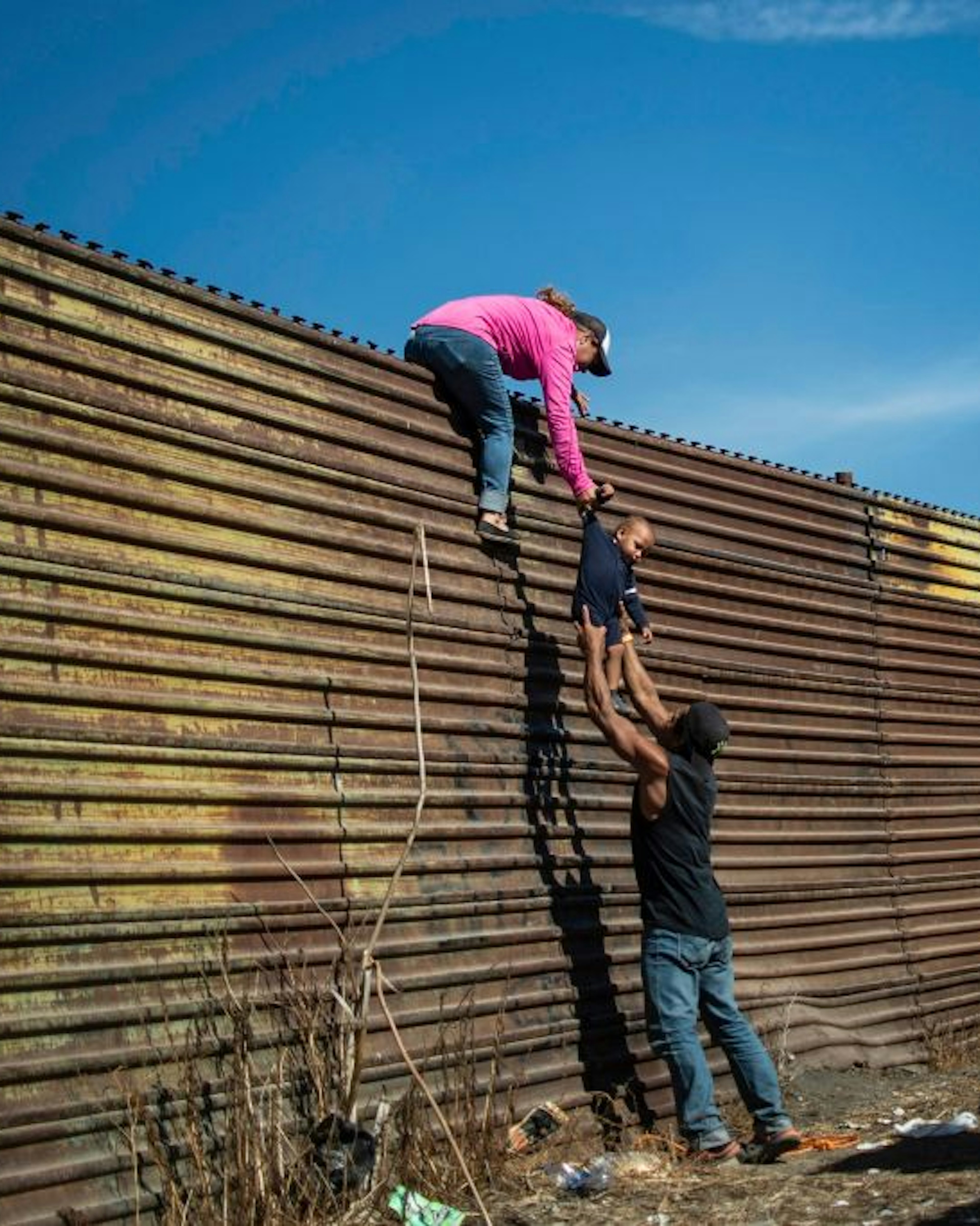 TOPSHOT - A group of Central American migrants climb the border fence between Mexico and the United States, near El Chaparral border crossing, in Tijuana, Baja California State, Mexico, on November 25, 2018. - Hundreds of migrants attempted to storm a border fence separating Mexico from the US on Sunday amid mounting fears they will be kept in Mexico while their applications for a asylum are processed. An AFP photographer said the migrants broke away from a peaceful march at a border bridge and tried to climb over a metal border barrier in the attempt to enter the United States. (Photo by Pedro PARDO / AFP) (Photo by PEDRO PARDO/AFP via Getty Images)