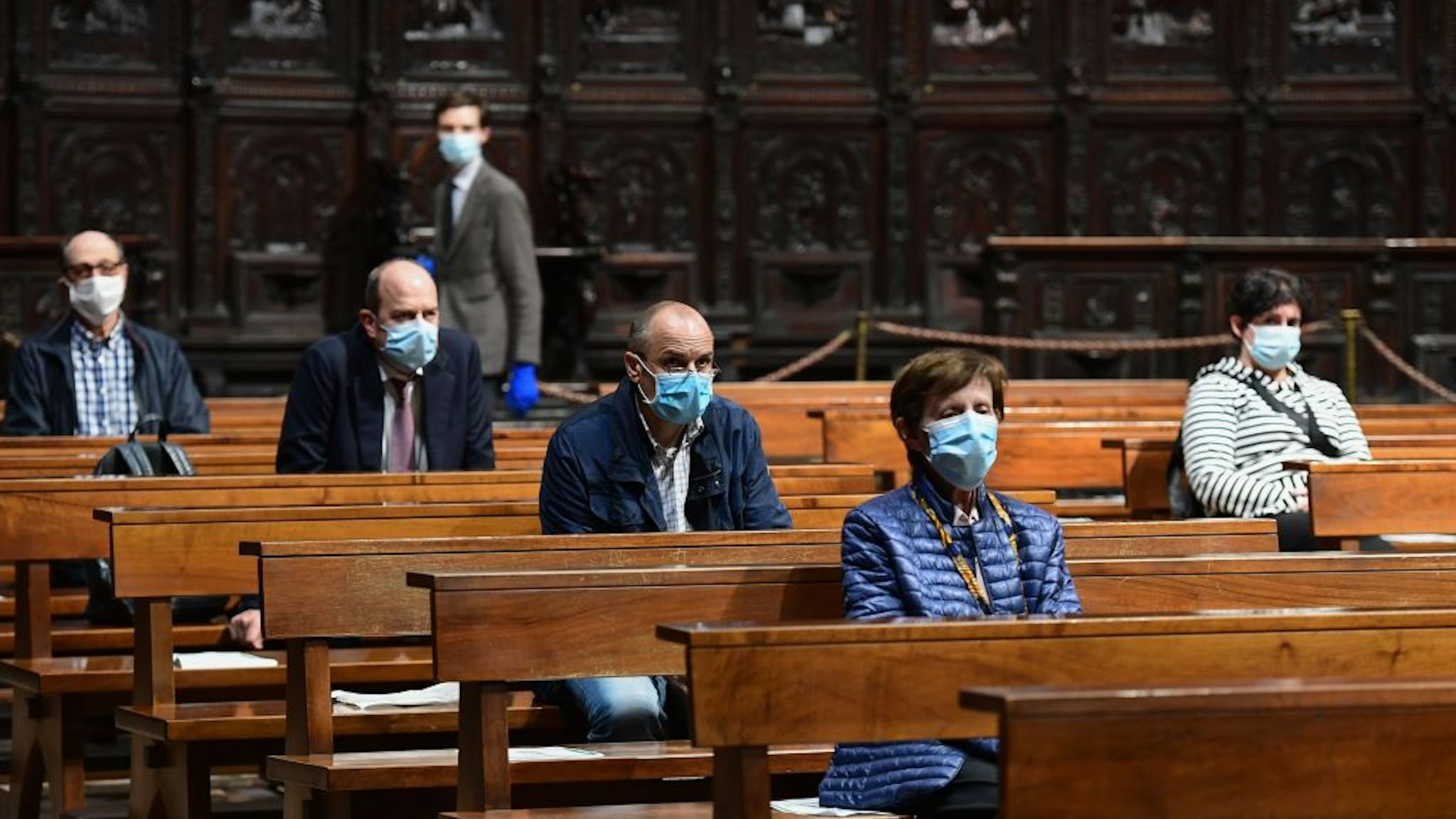 People attend a mass at the Cappella Feriale chapel of the Duomo cathedral in Milan on May 18, 2020 during the country's lockdown aimed at curbing the spread of the COVID-19 infection, caused by the novel coronavirus. - Restaurants and churches reopen in Italy on May 18, 2020 as part of a fresh wave of lockdown easing in Europe and the country's latest step in a cautious, gradual return to normality, allowing businesses and churches to reopen after a two-month lockdown. (Photo by Miguel MEDINA / AFP) (Photo by MIGUEL MEDINA/AFP via Getty Images)