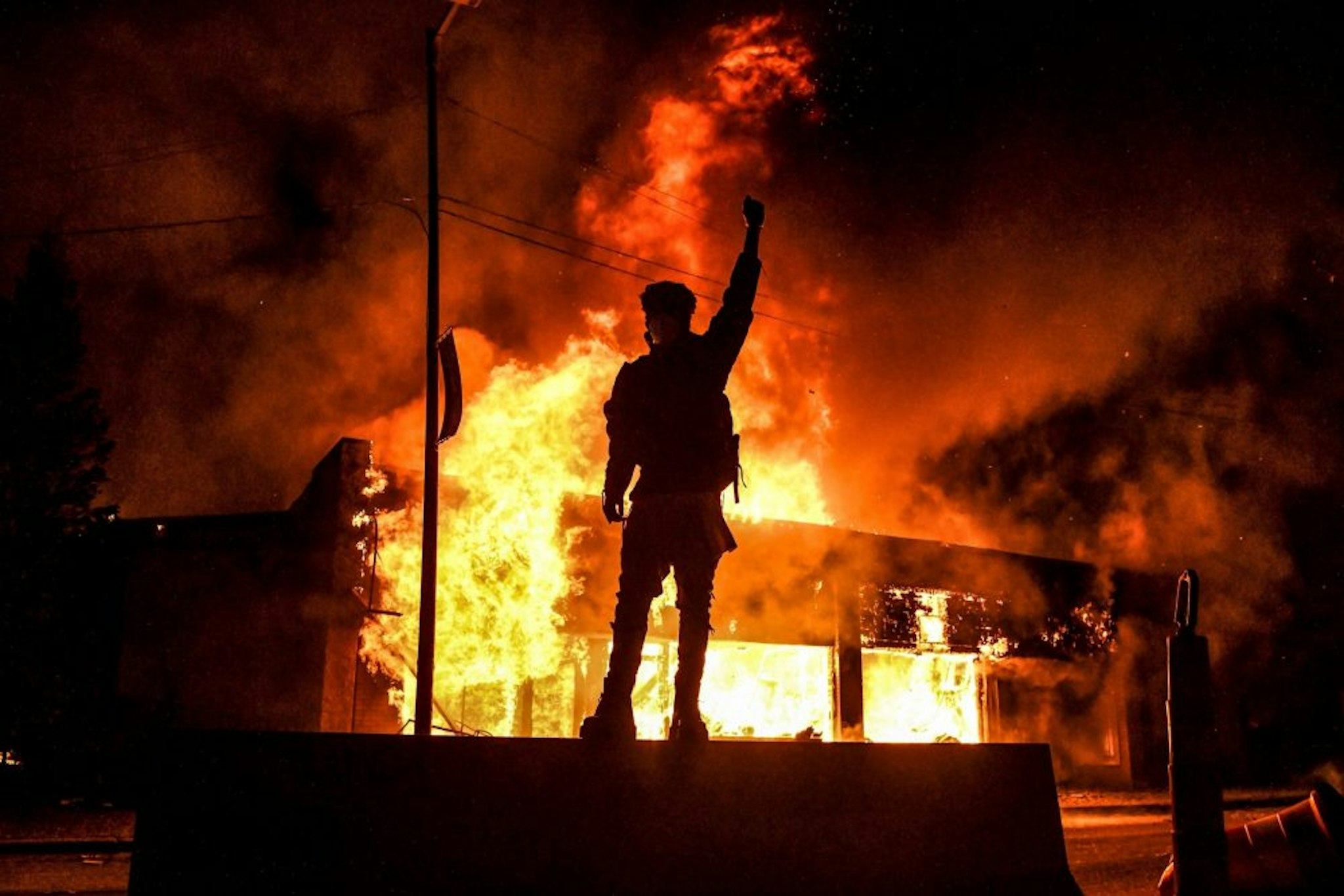 TOPSHOT - A protester reacts standing in front of a burning building set on fire during a demonstration in Minneapolis, Minnesota, on May 29, 2020, over the death of George Floyd, a black man who died after a white policeman kneeled on his neck for several minutes. - Violent protests erupted across the United States late on May 29 over the death of a handcuffed black man in police custody, with murder charges laid against the arresting Minneapolis officer failing to quell seething anger.