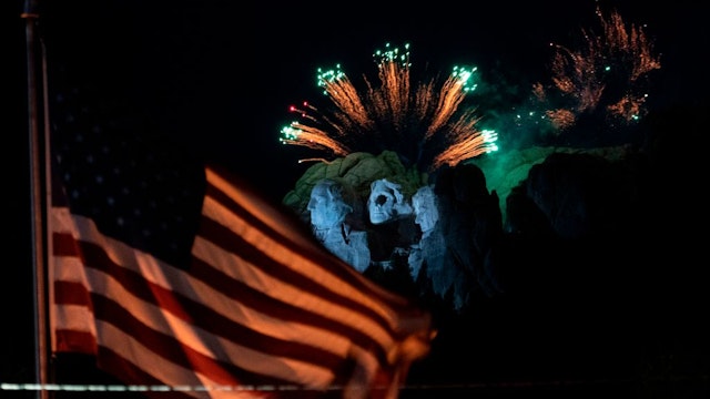 A US flag flies as fireworks explode above the Mount Rushmore National Monument during an Independence Day event attended by the US president in Keystone, South Dakota, July 3, 2020
