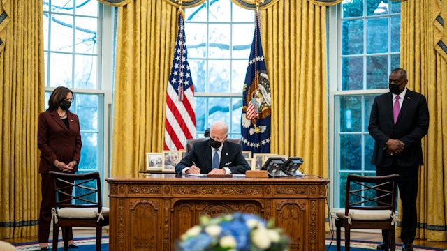 WASHINGTON, DC - JANUARY 25: Flanked by Vice President Kamala Harris (L) and Secretary of Defense Lloyd Austin (R), U.S. President Joe Biden signs an executive order in the Oval Office of the White House on January 25, 2021 in Washington, DC. President Biden signed an executive order repealing the ban on transgender people serving openly in the military. (Photo by Doug Mills-Pool/Getty Images)