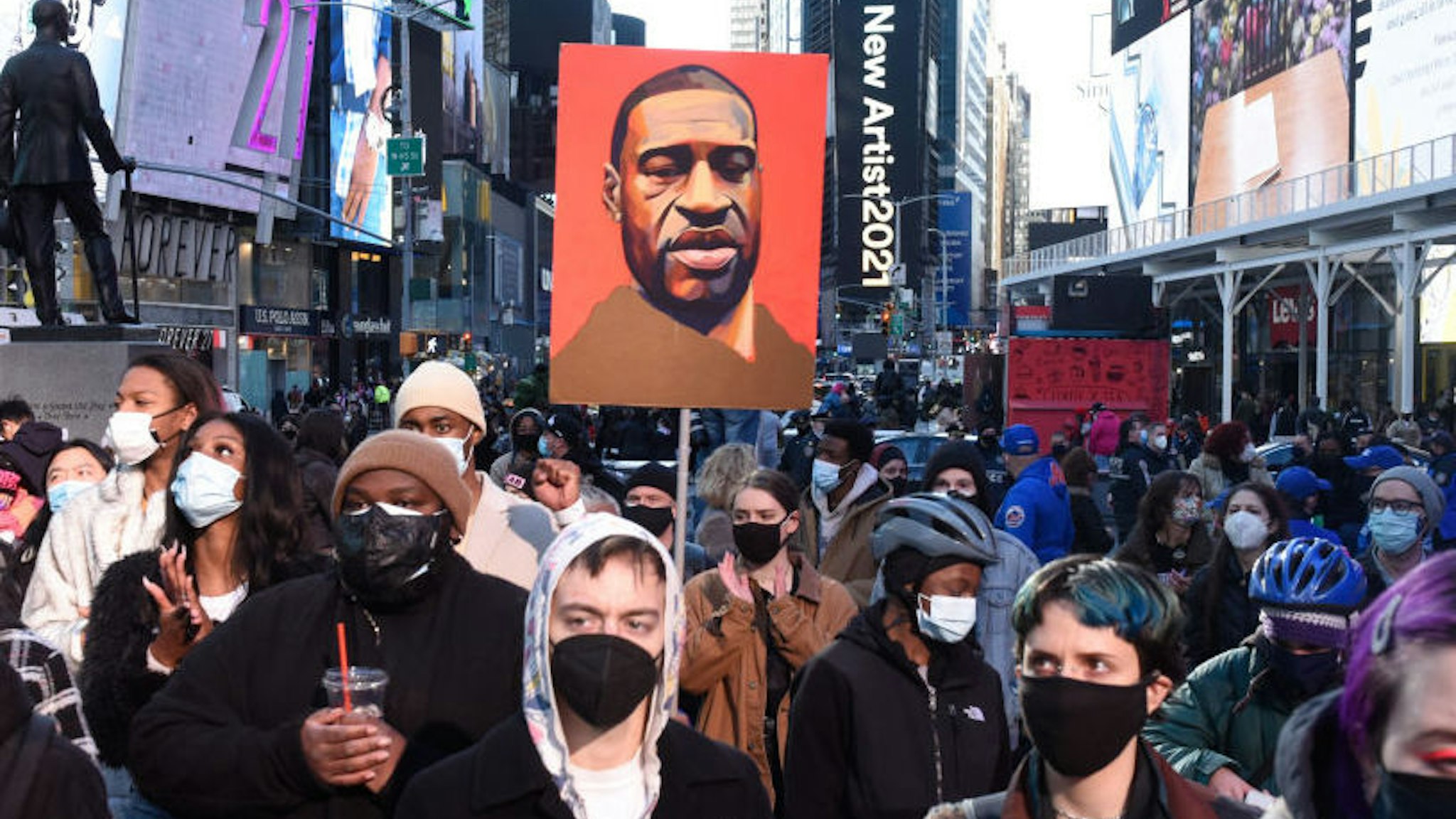 A person holds a placard with George Floyd's face during a protest to mark the one year anniversary of Breonna Taylor's death on March 13, 2021 in New York City.
