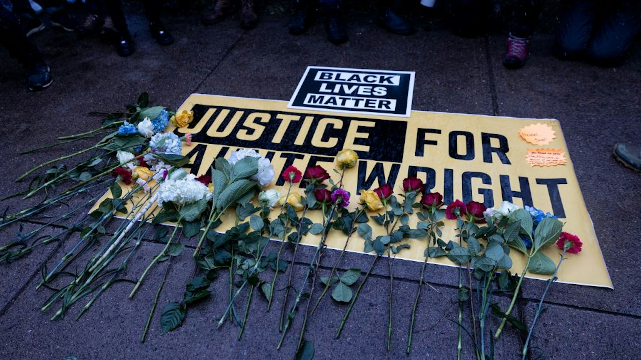 People lay flowers on a sign as they rally outside the Brooklyn Center police station to protest the death of Daunte Wright who was shot and killed by a police officer in Brooklyn Center, Minnesota on April 13, 2021. - Tensions have soared over the death on April 11 of African American Daunte Wright near the Midwestern US city, a community already on edge over the ongoing trial of a policeman accused of killing another Black man, George Floyd. (Photo by Kerem YUCEL / AFP) (Photo by KEREM YUCEL/AFP via Getty Images)