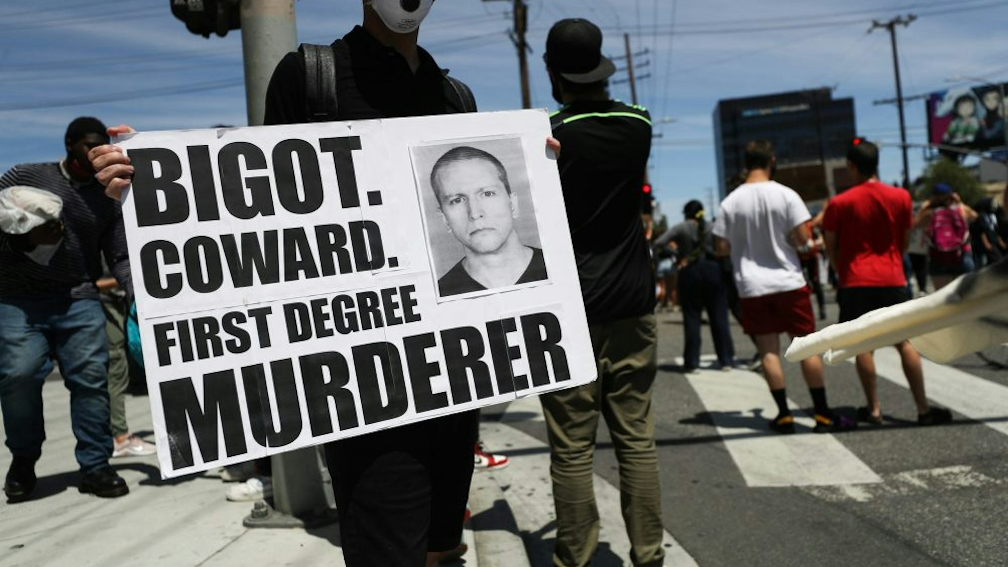 LOS ANGELES, CALIFORNIA - MAY 30: A protester holds a sign with a photo of former Minneapolis police officer Derek Chauvin during demonstrations following the death of George Floyd on May 30, 2020 in Los Angeles, California. Chauvin was taken into custody for Floyd's death. Chauvin has been accused of kneeling on Floyd's neck as he pleaded with him about not being able to breathe. Floyd was pronounced dead a short while later. Chauvin and 3 other officers, who were involved in the arrest, were fired from the police department after a video of the arrest was circulated.