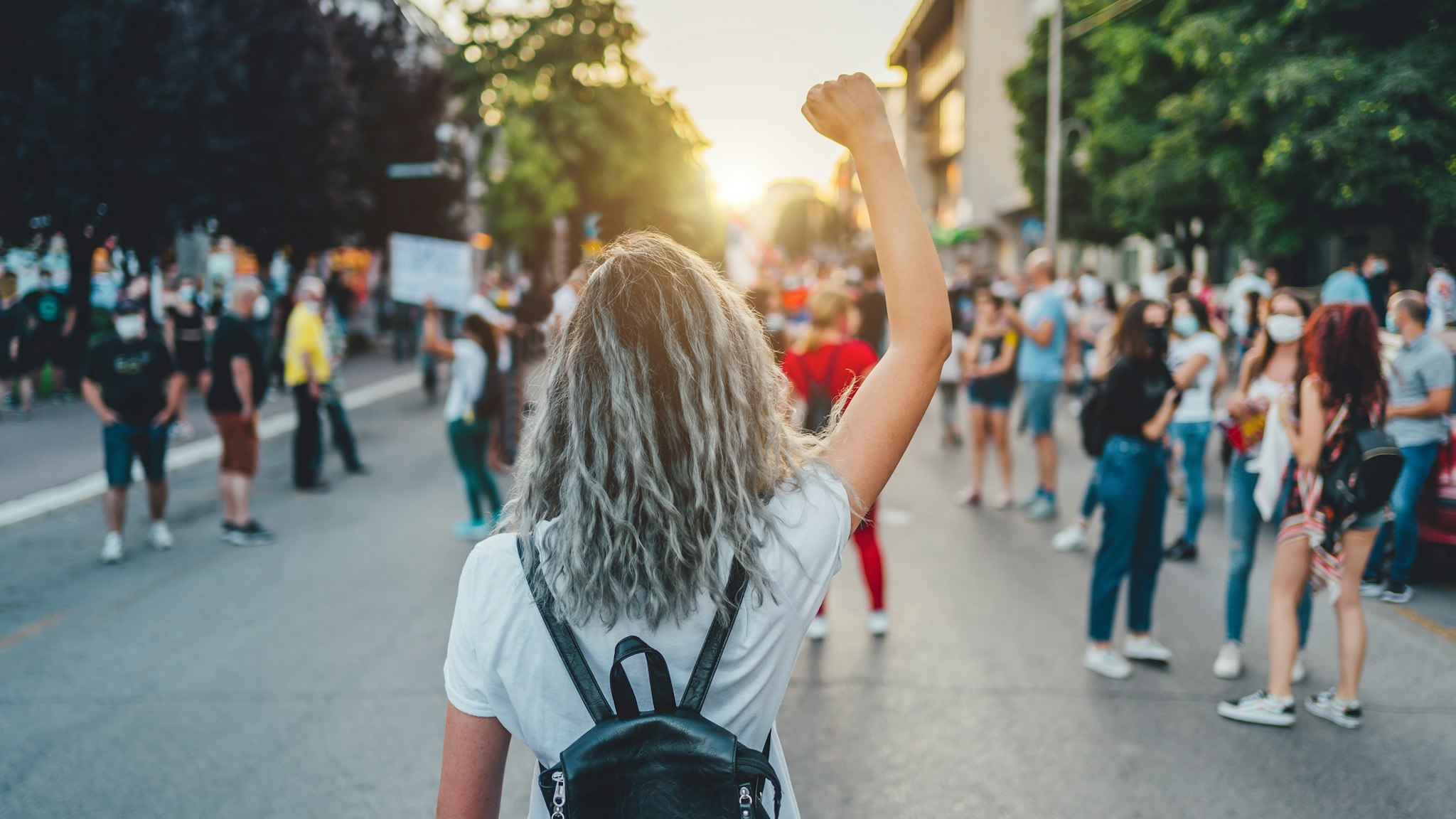 Young woman protester raising her fist up - stock photo